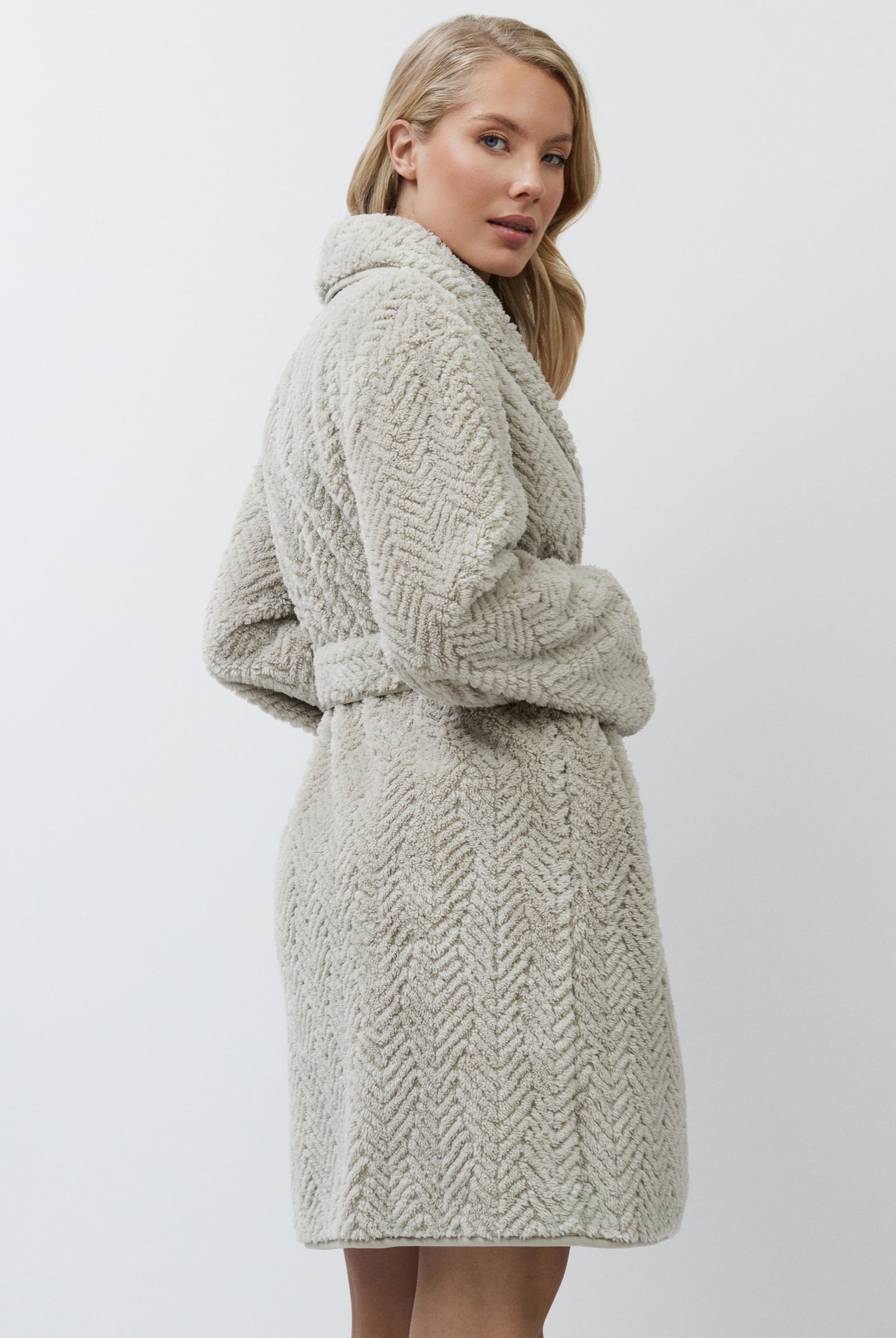 Woman wearing a textured beige bathrobe against a white background