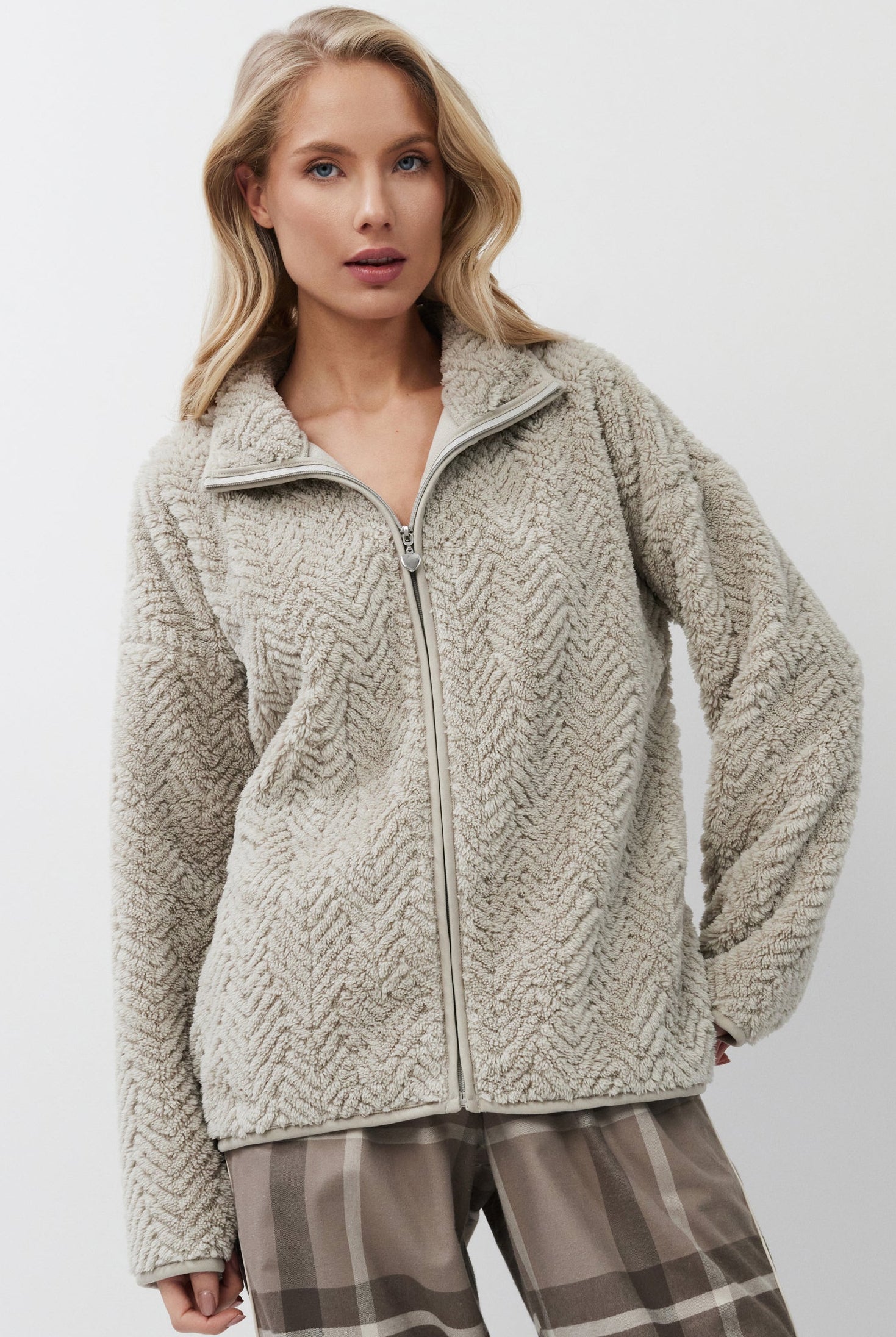 Woman wearing a sweater and plaid pants on a white background