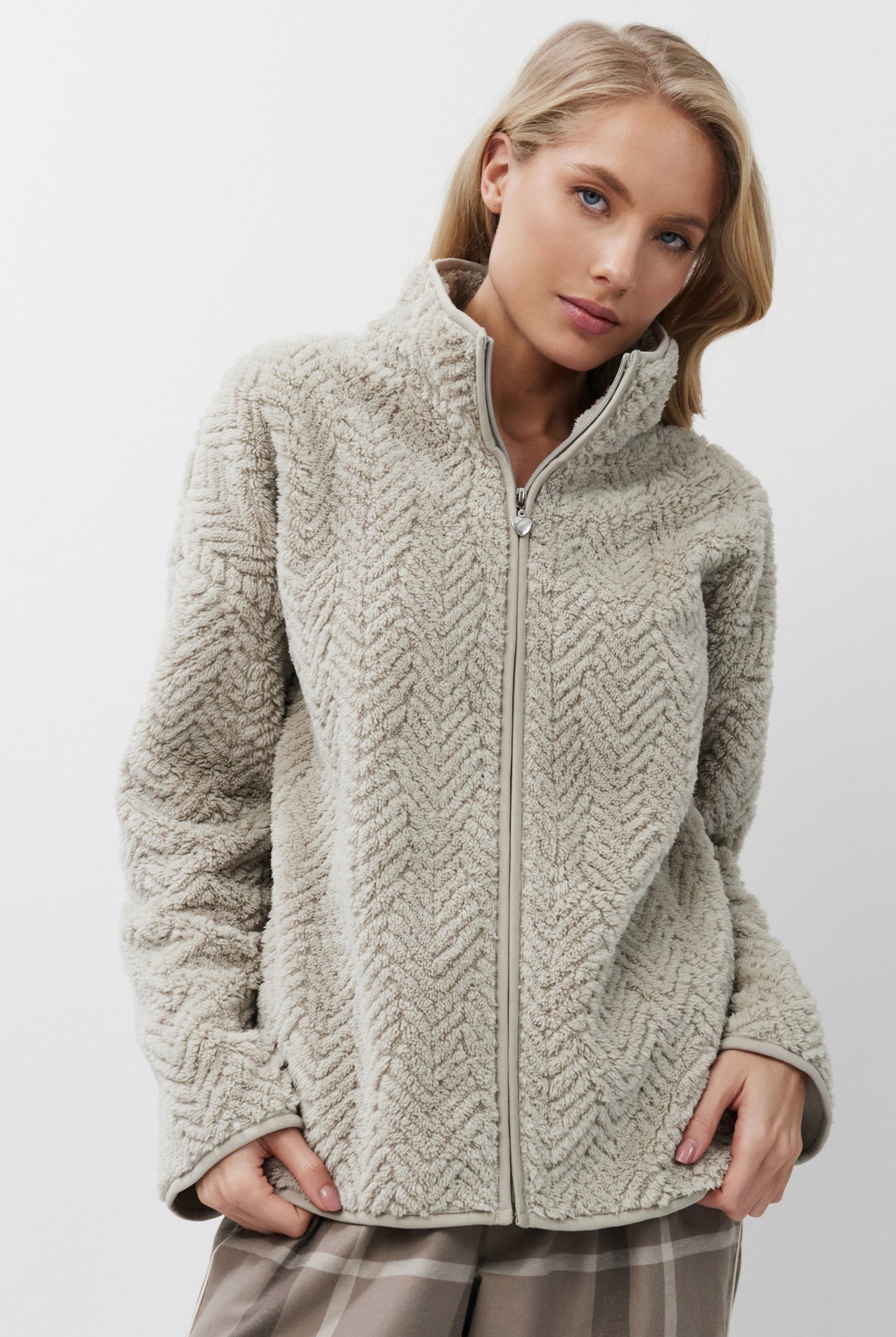 Woman wearing a sweater and plaid pants on a white background