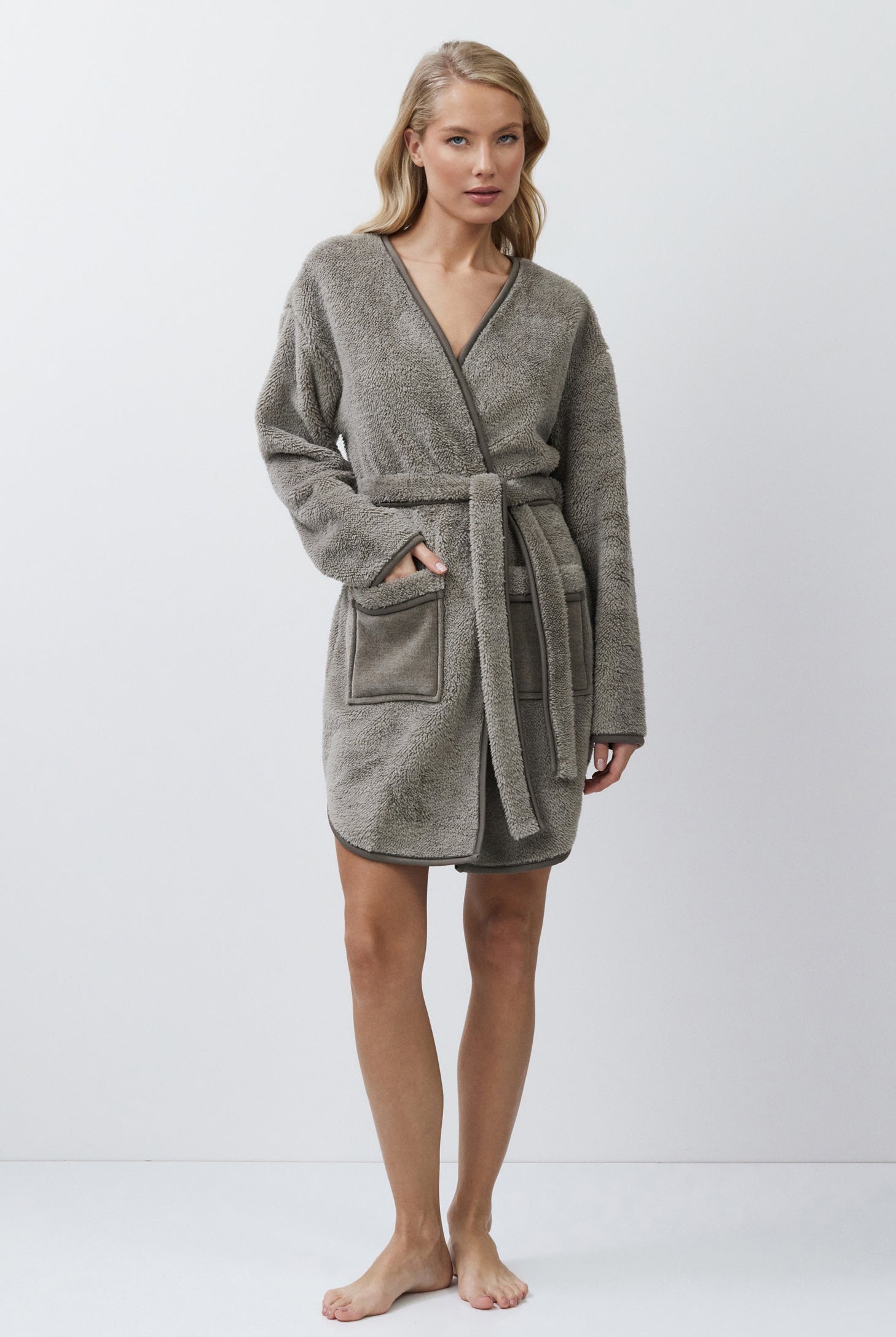 Woman wearing a gray bathrobe on a white background