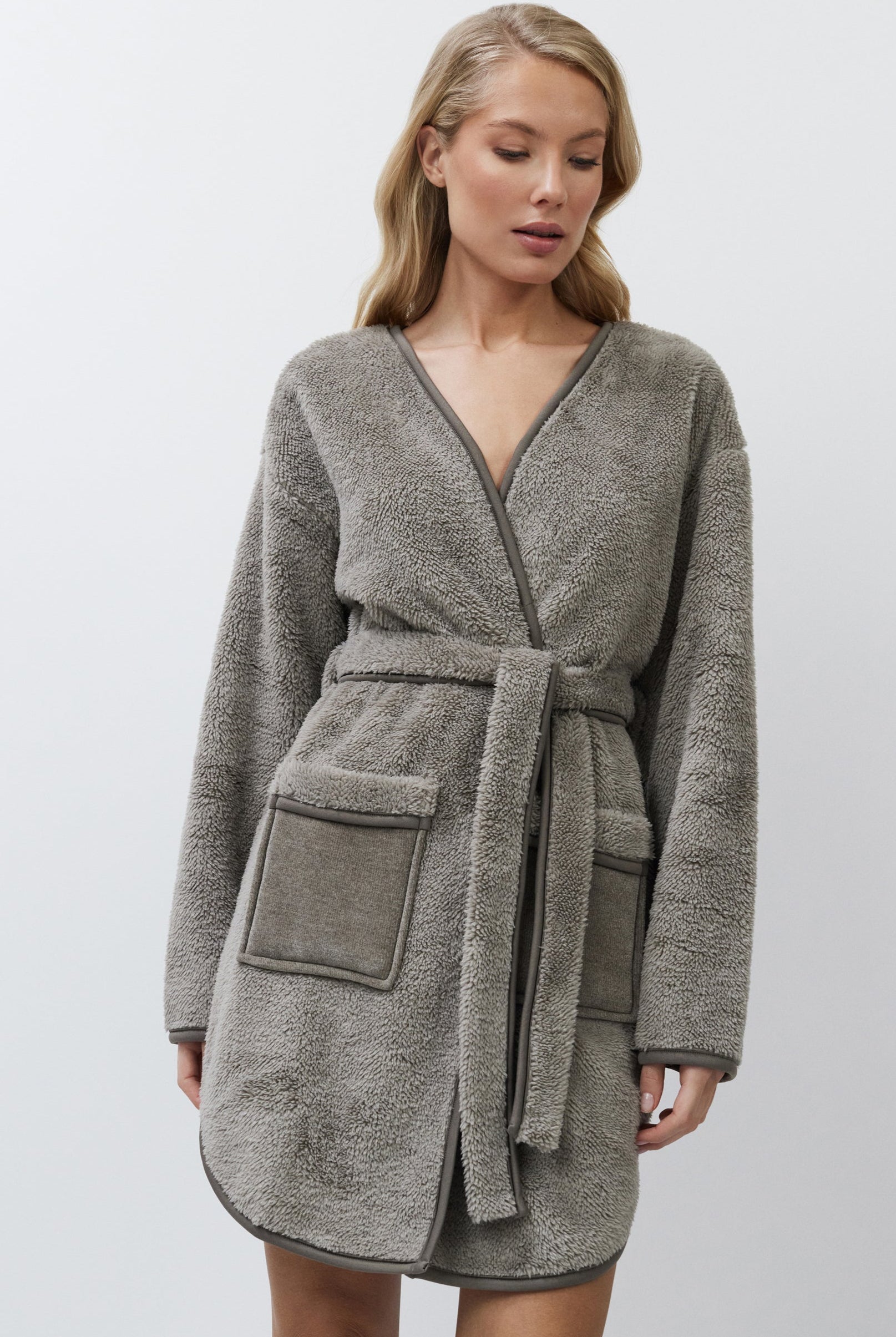 Woman wearing a gray bathrobe on a white background