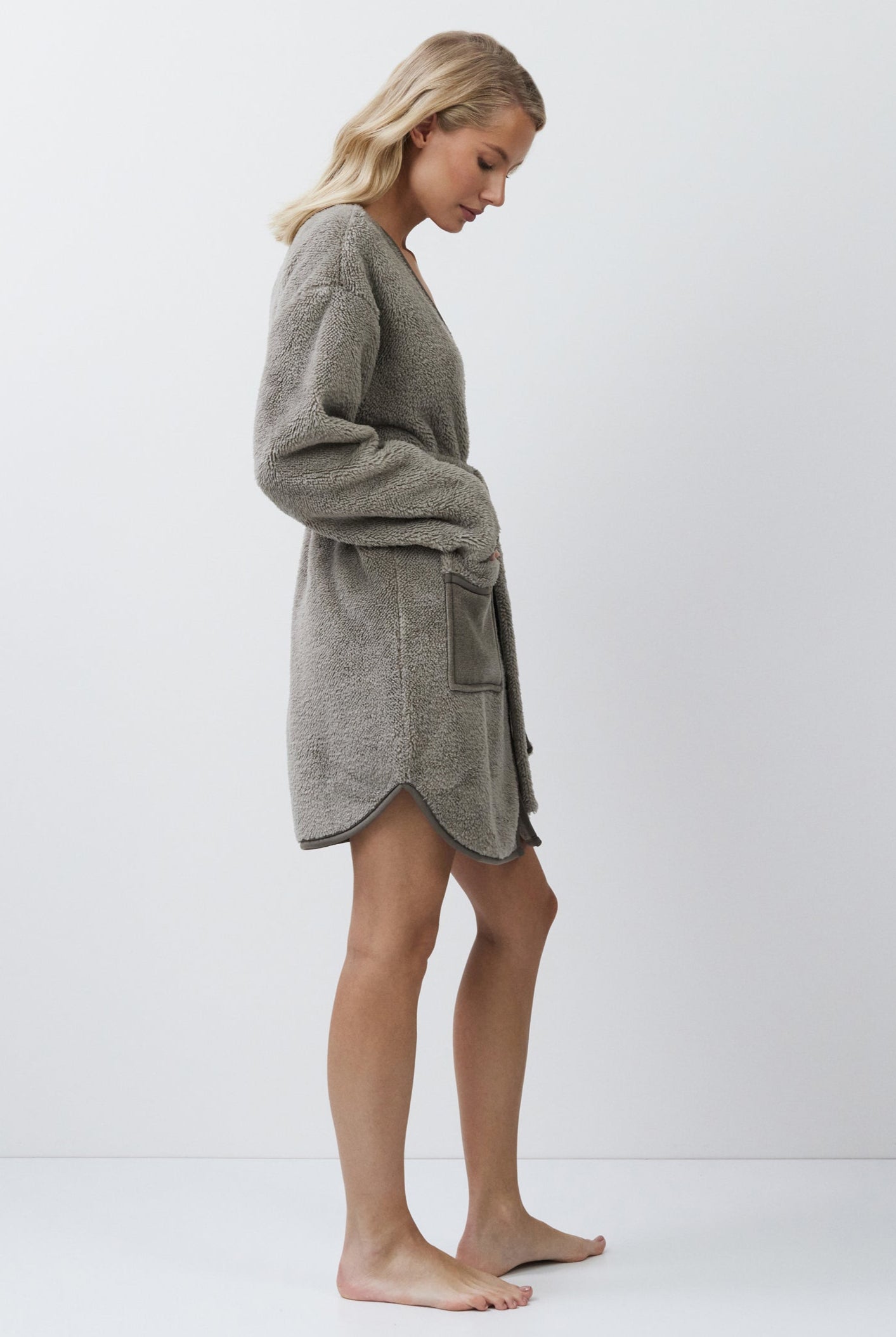 Woman wearing a gray bathrobe against a white background