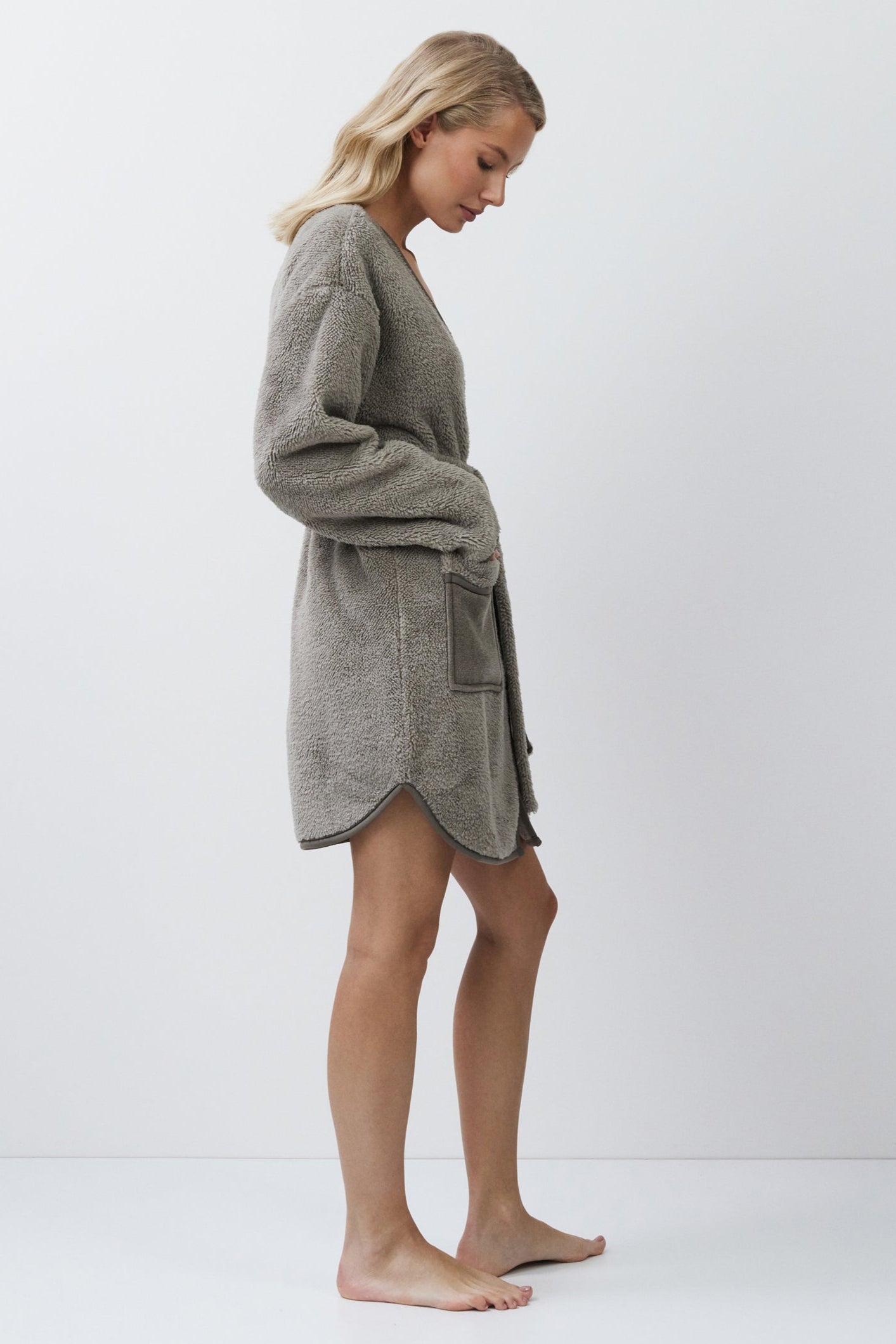 Woman wearing a gray bathrobe against a white background