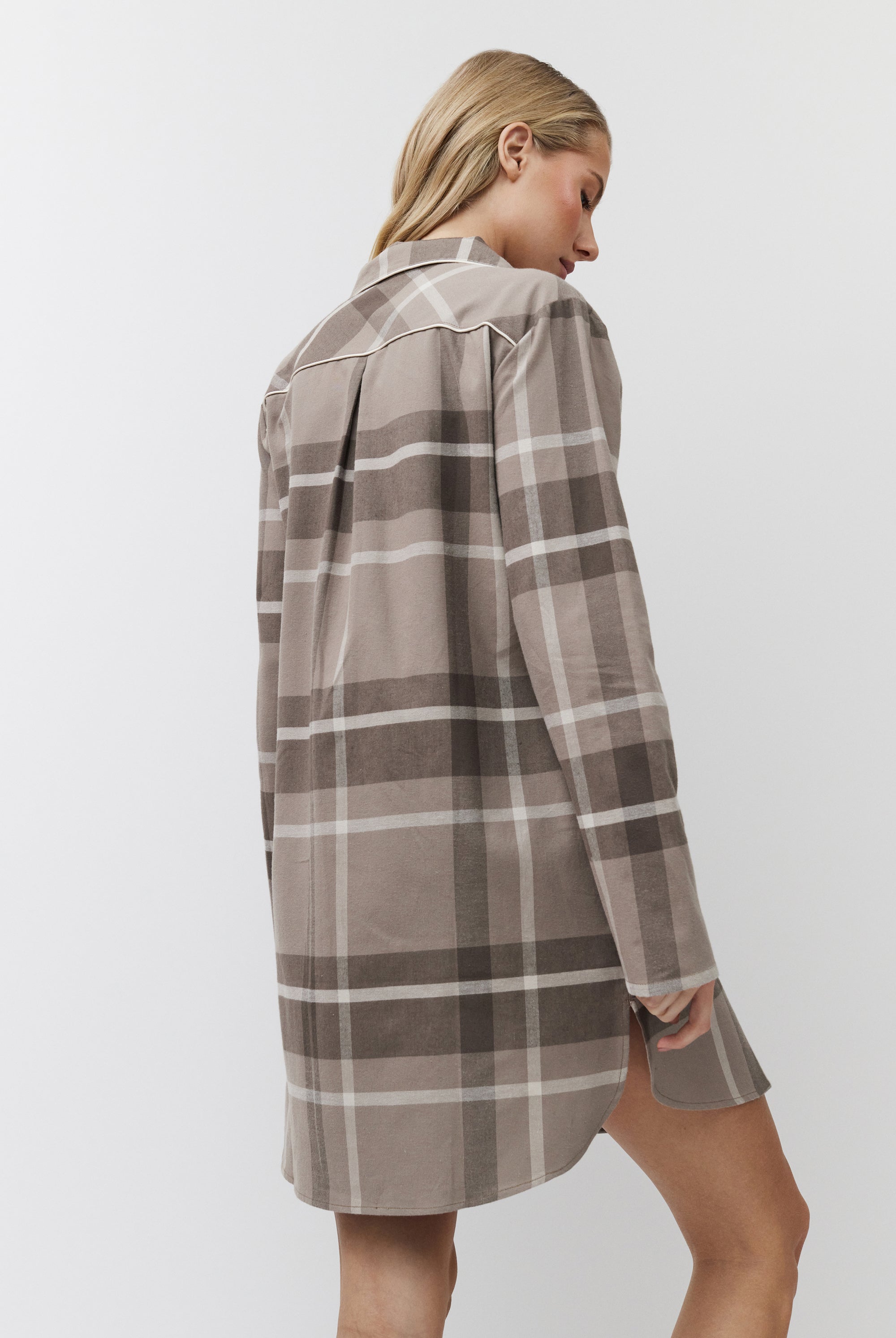 Woman wearing a plaid shirt dress against a white background