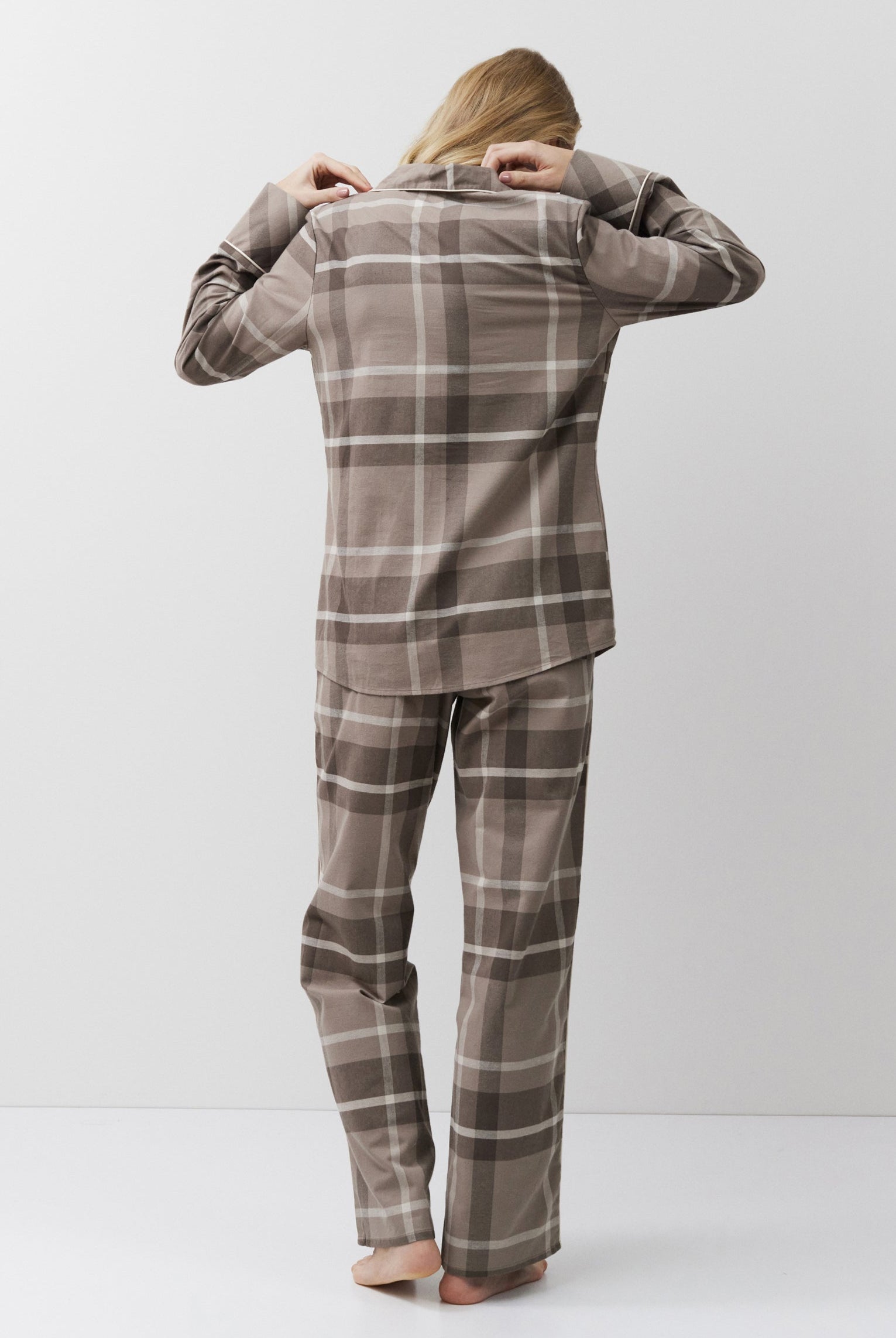Person wearing a plaid pajama set standing against a white background