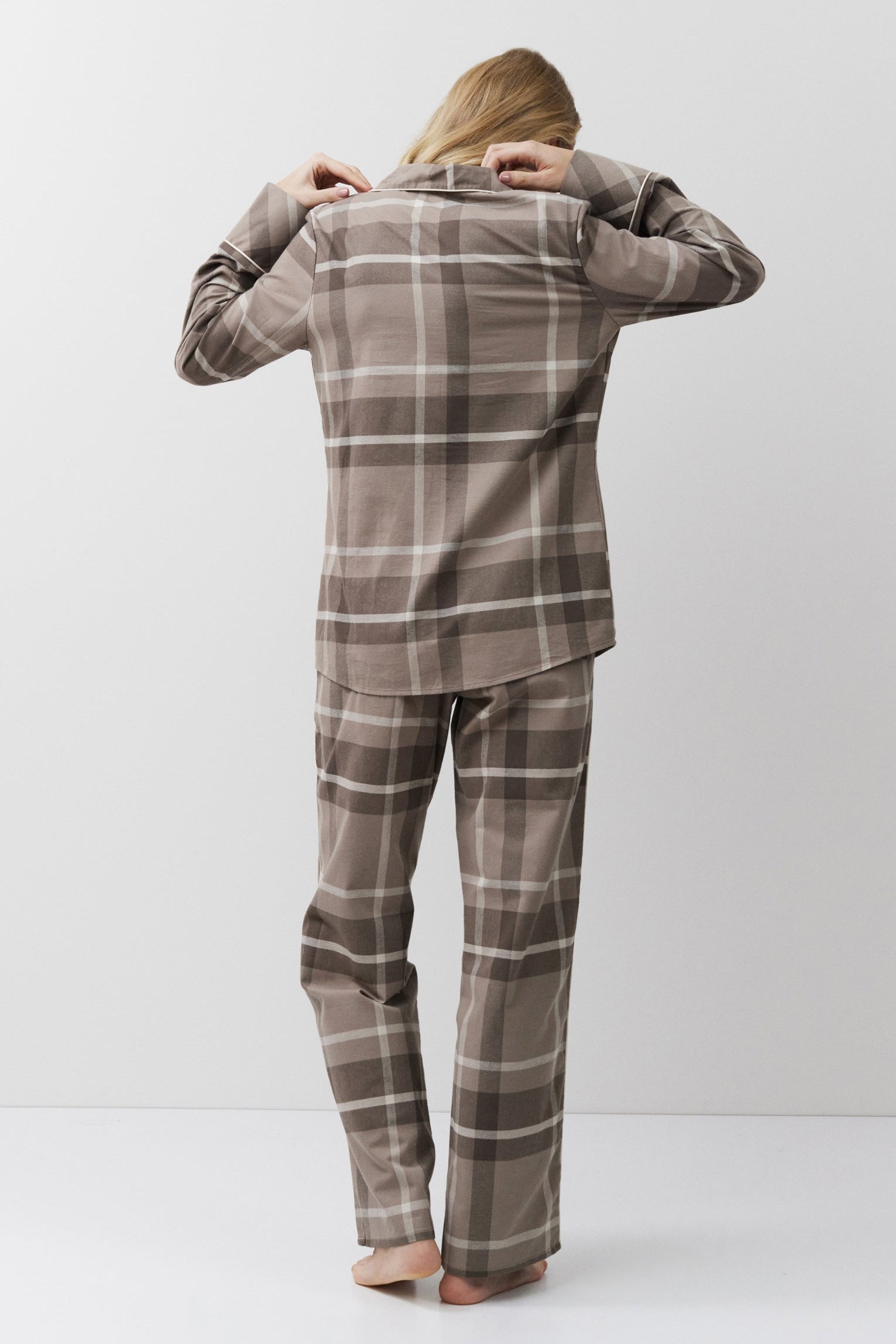 Person wearing a plaid pajama set standing against a white background
