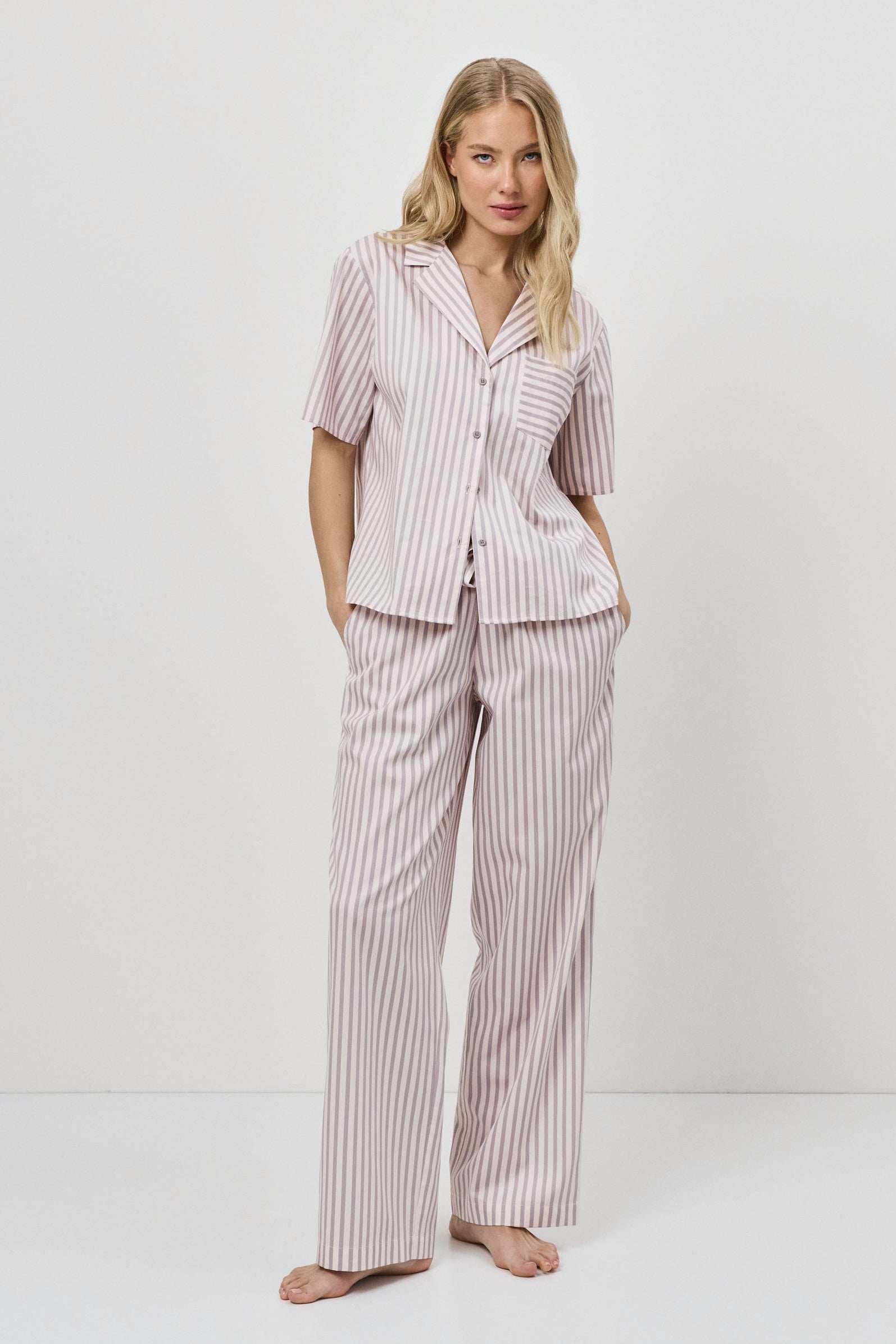 Woman wearing a pink striped pajama set against a white background