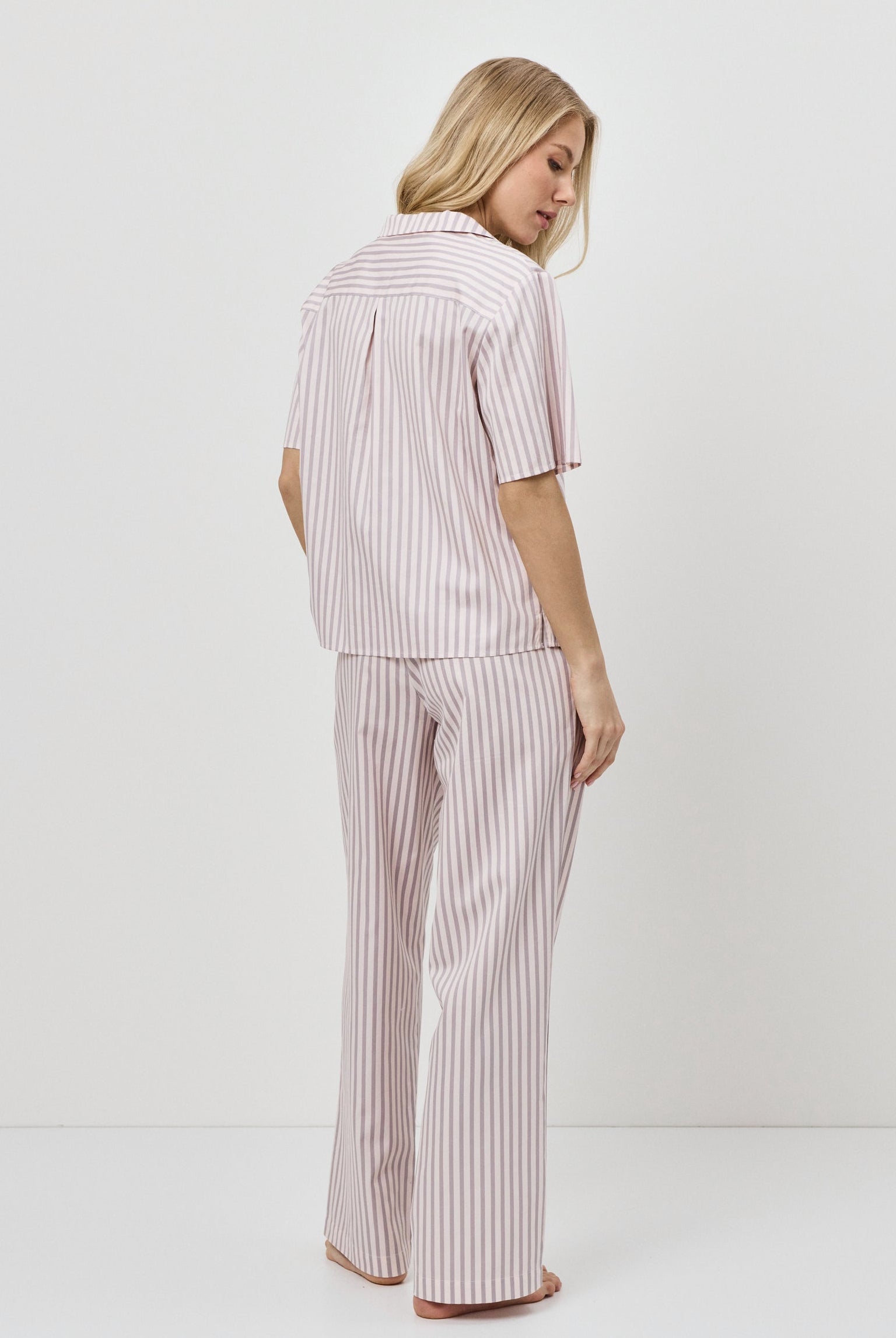 Woman wearing a pink striped pajama set on a white background