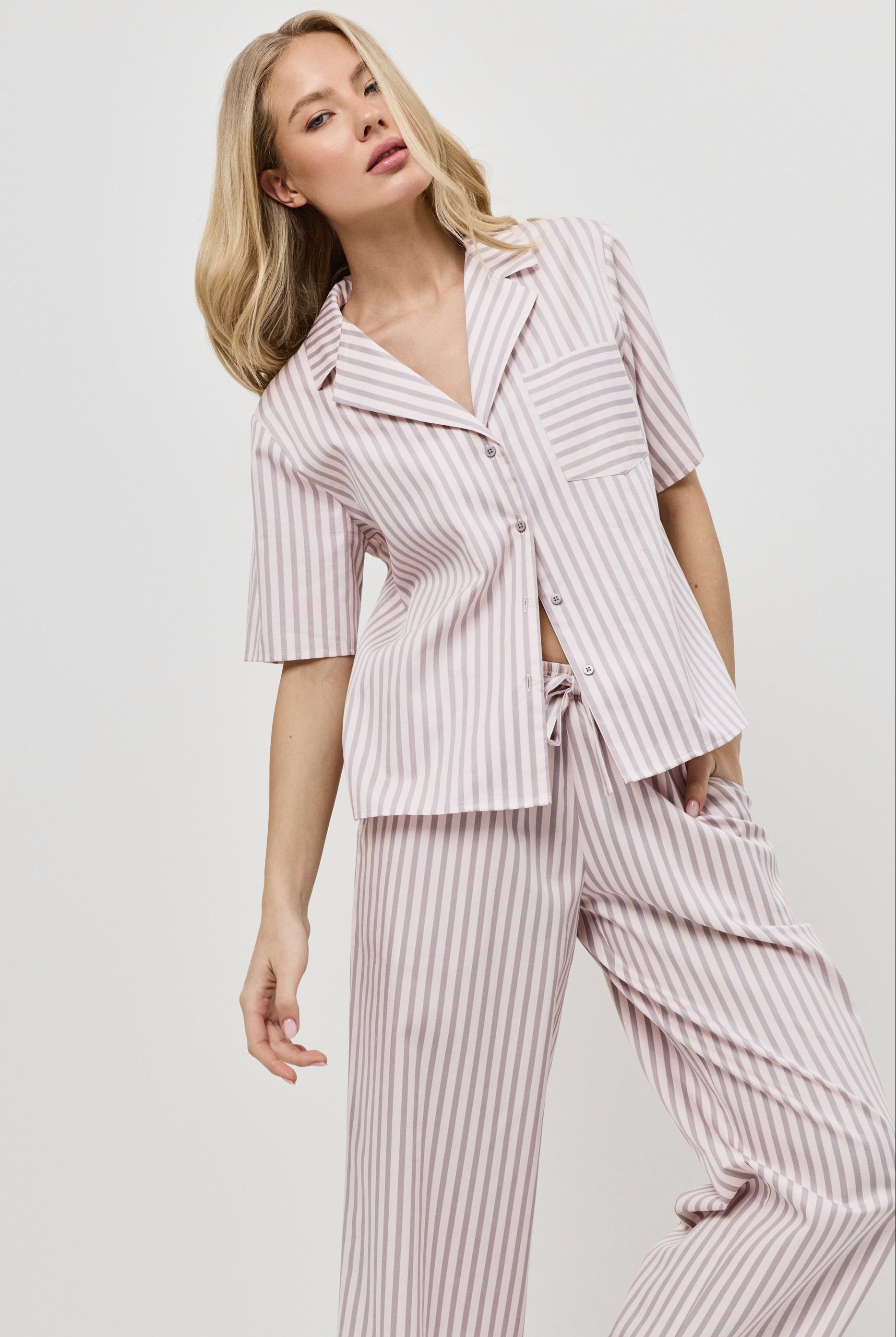 Woman wearing a pink striped outfit on a plain background