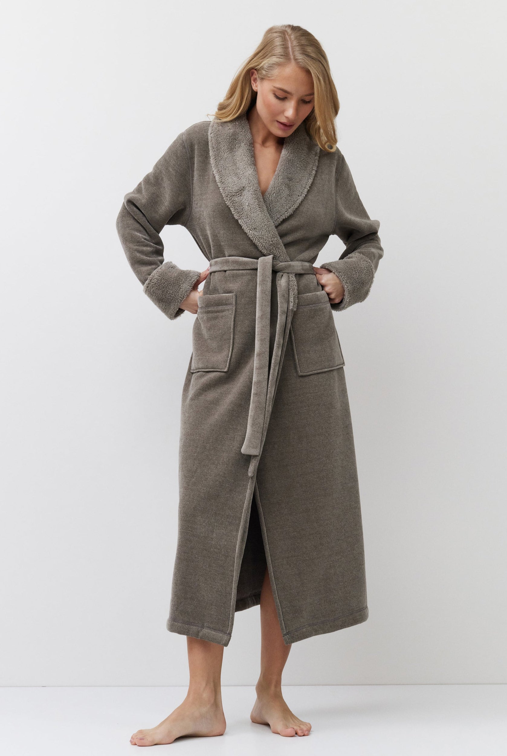 Woman wearing a long brown bathrobe against a white background