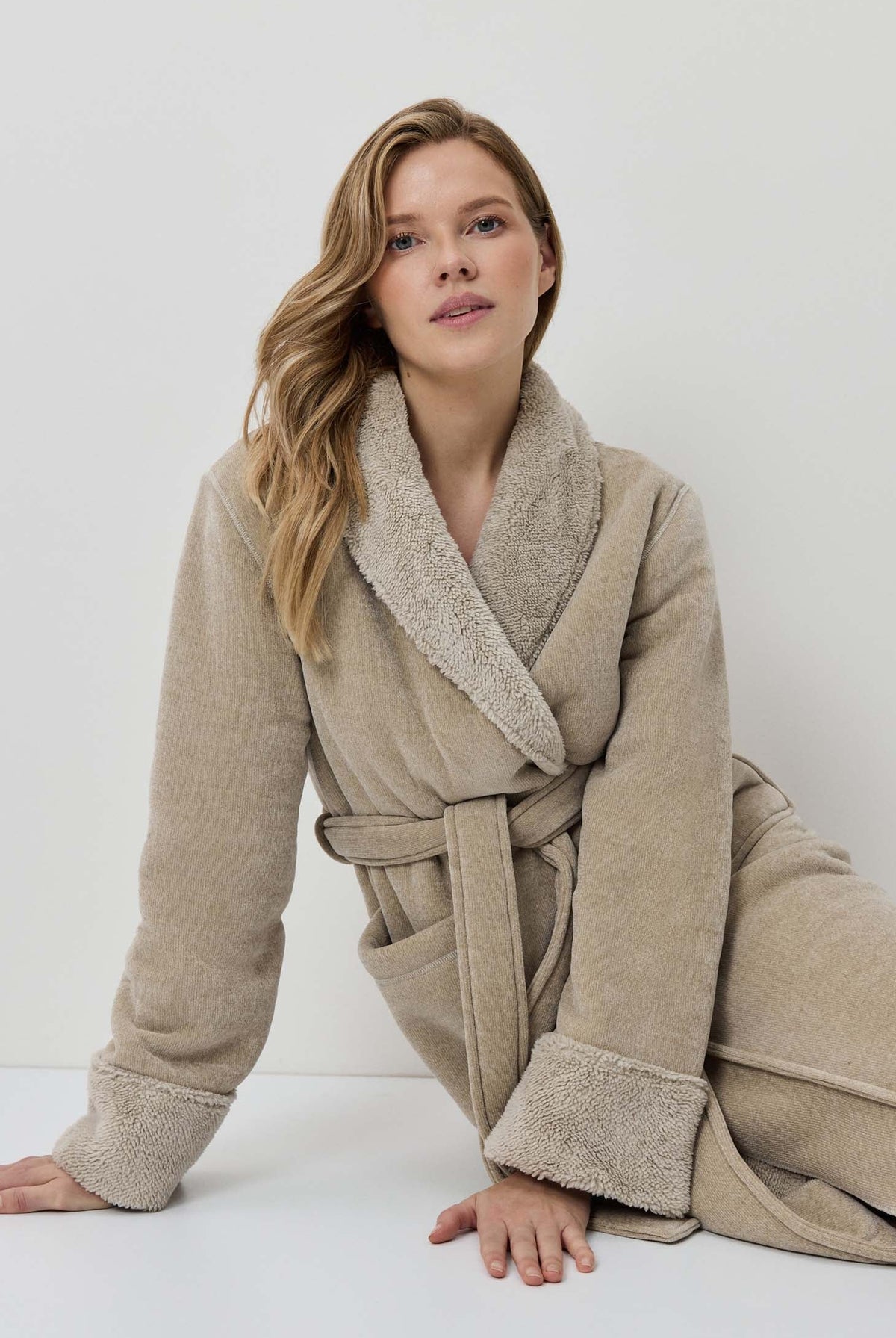 Woman wearing a beige robe against a white background