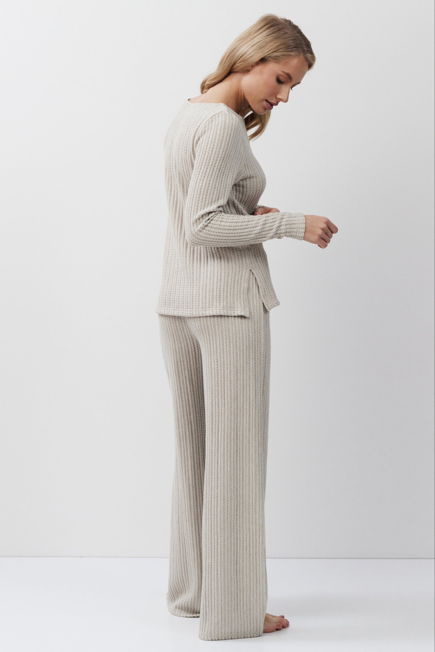 Woman wearing a beige suit standing against a white background