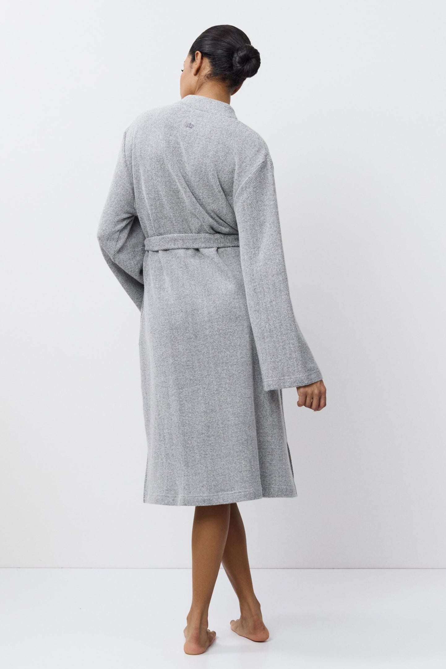 Person wearing a gray bathrobe against a white background