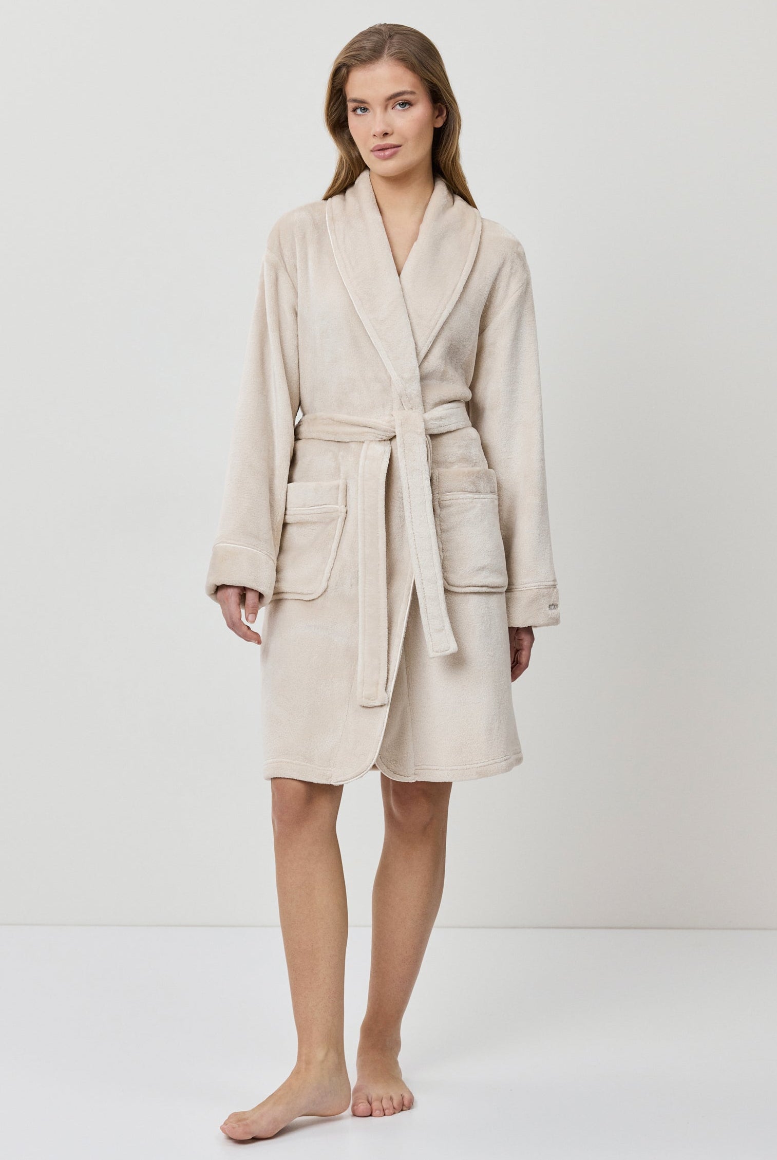 Woman wearing a beige bathrobe on a white background