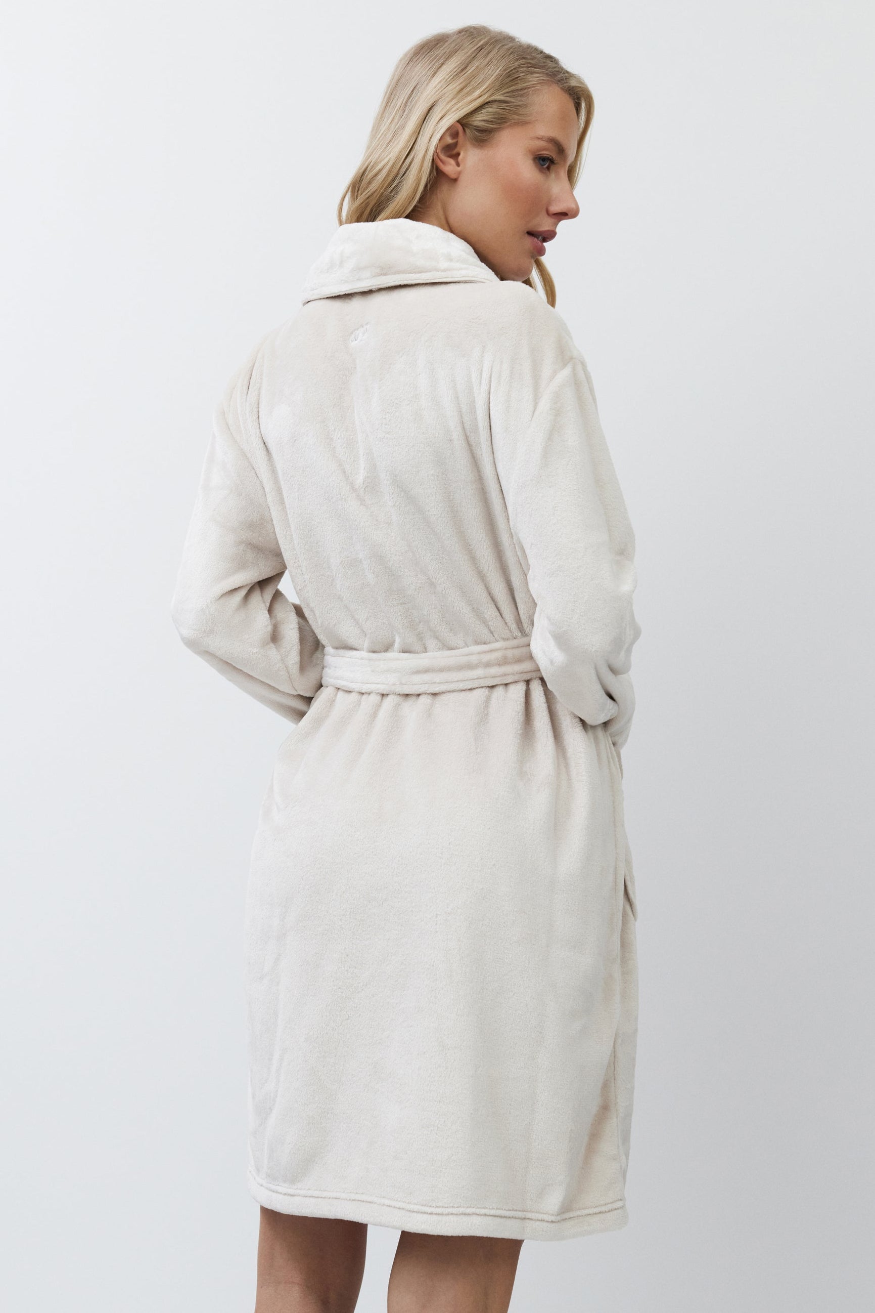 Woman wearing a beige bathrobe against a white background
