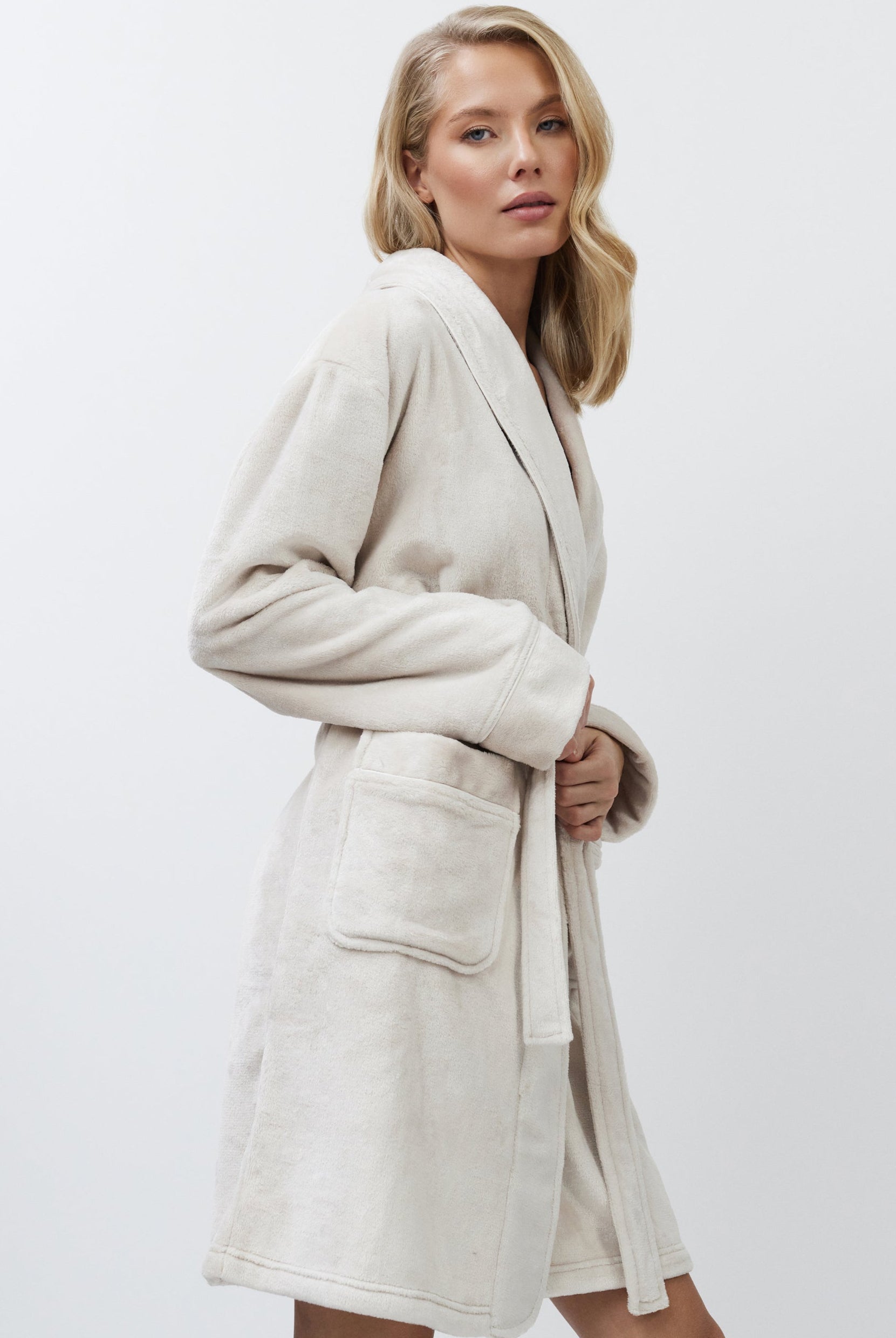 Woman wearing a beige bathrobe against a white background