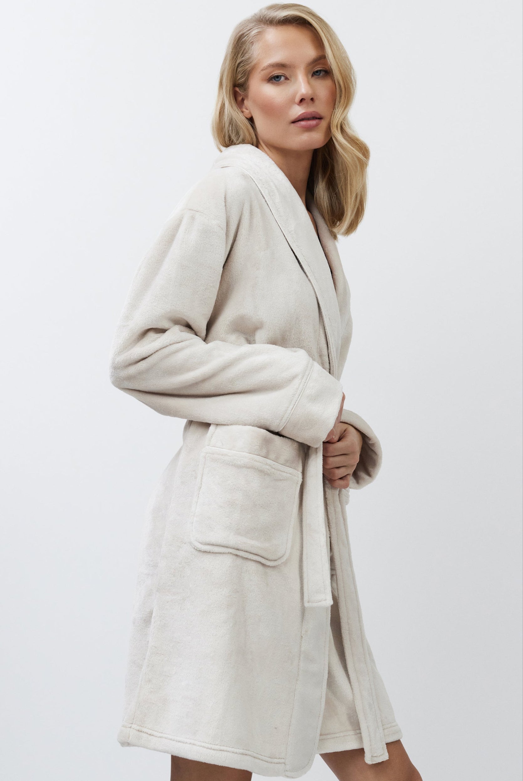 Woman wearing a beige bathrobe against a white background