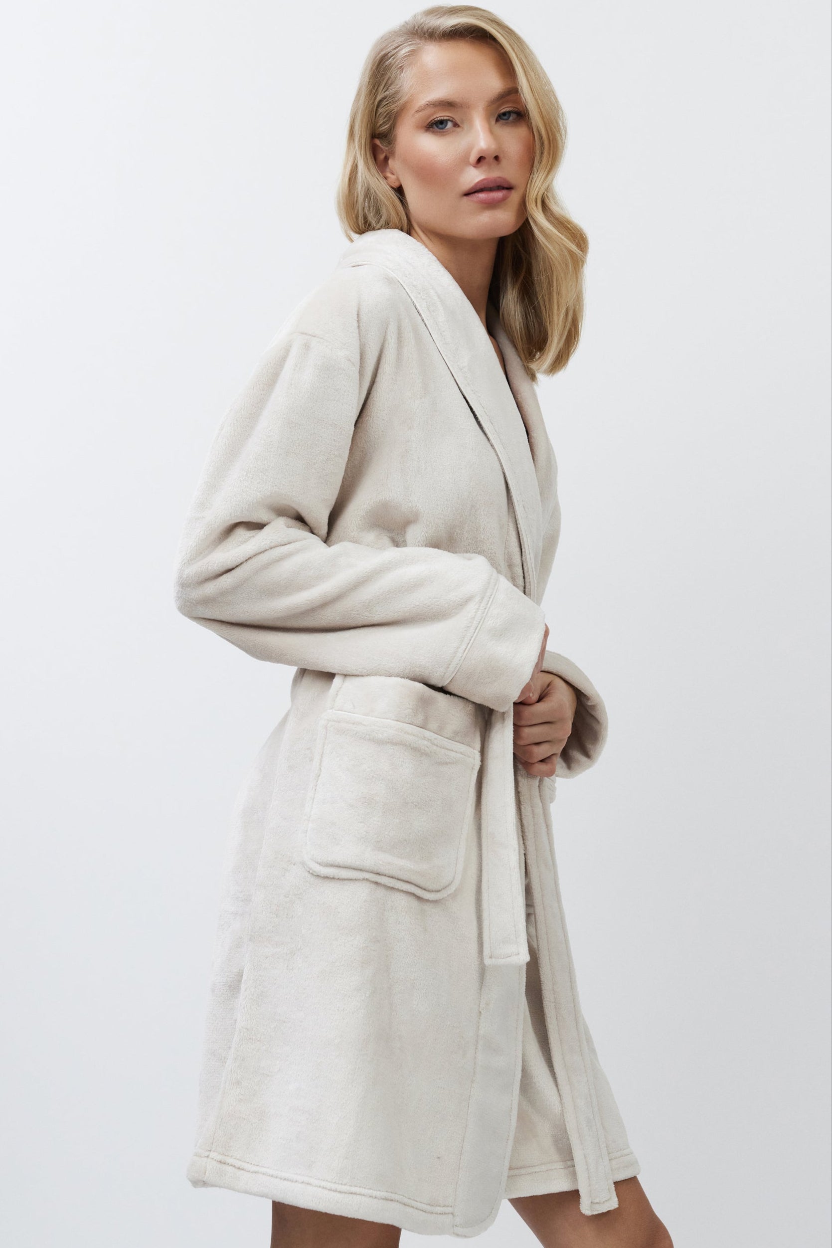 Woman wearing a beige bathrobe against a white background