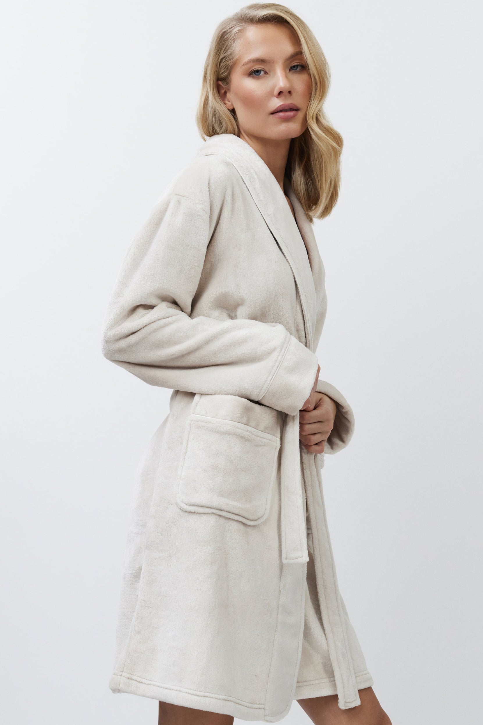 Woman wearing a beige bathrobe against a white background