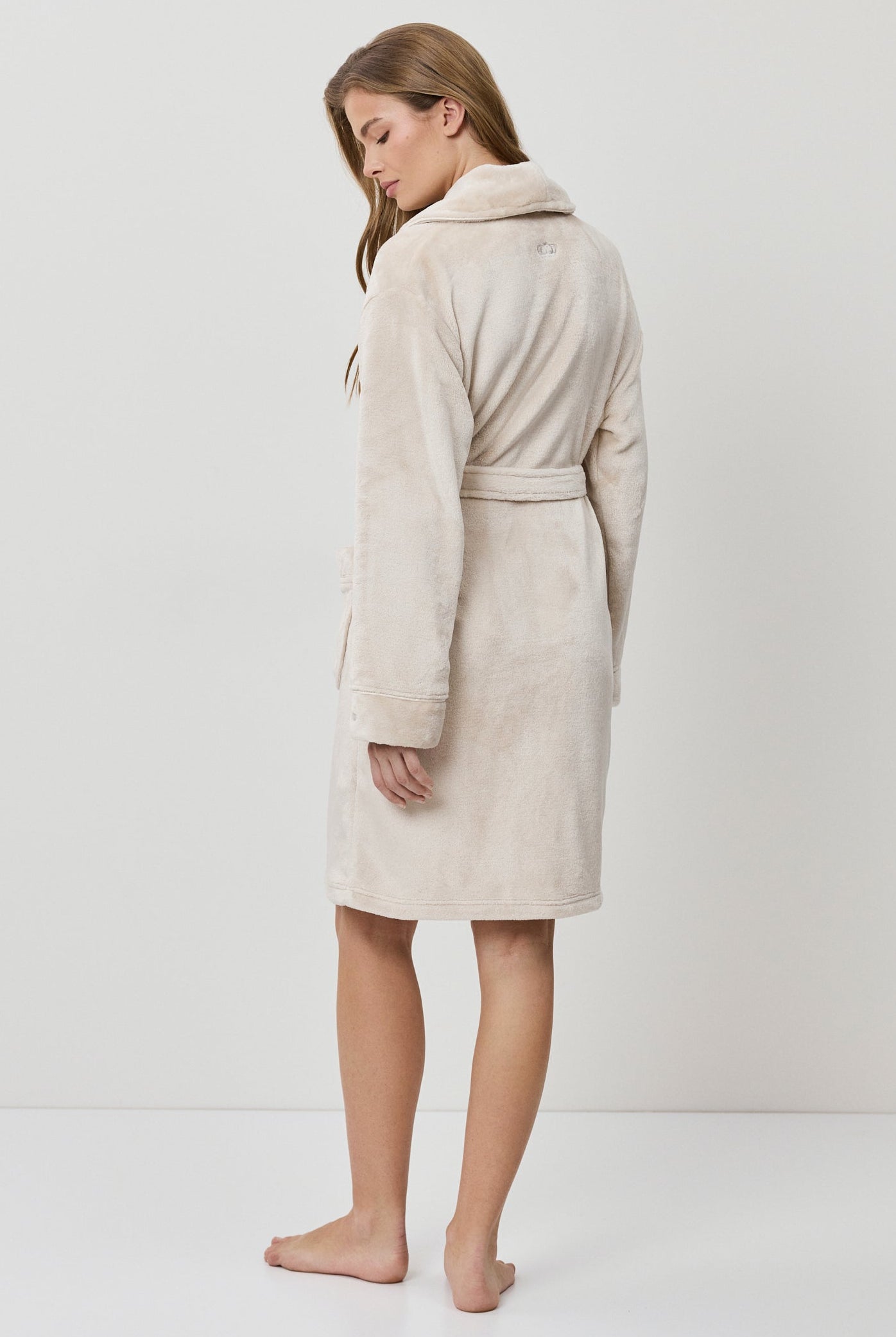 Woman wearing a beige bathrobe on a white background