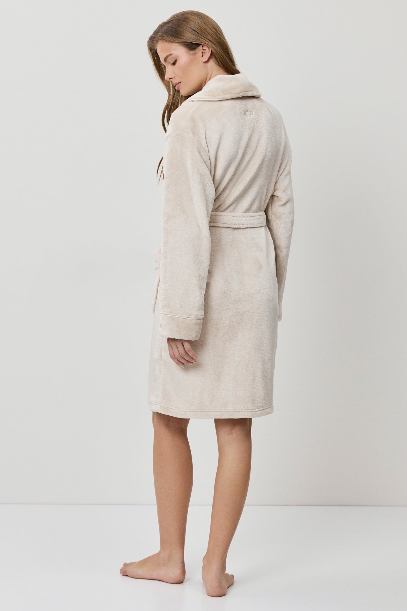 Woman wearing a beige bathrobe on a white background