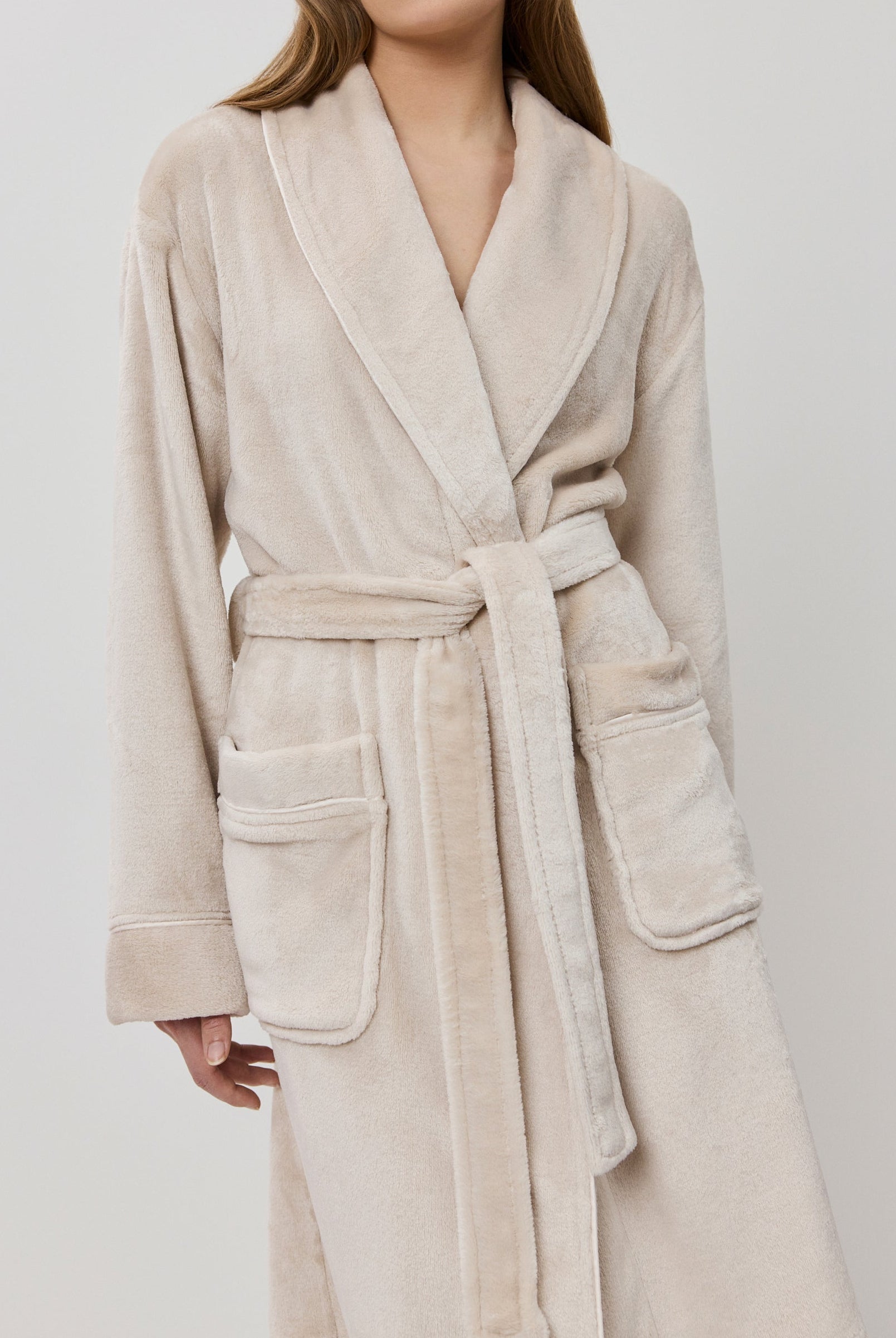 Woman wearing a beige bathrobe on a white background