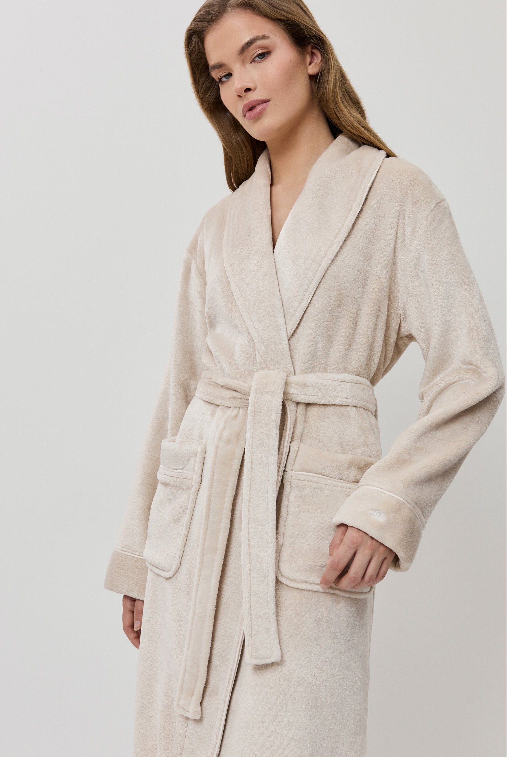 Woman wearing a beige bathrobe on a white background