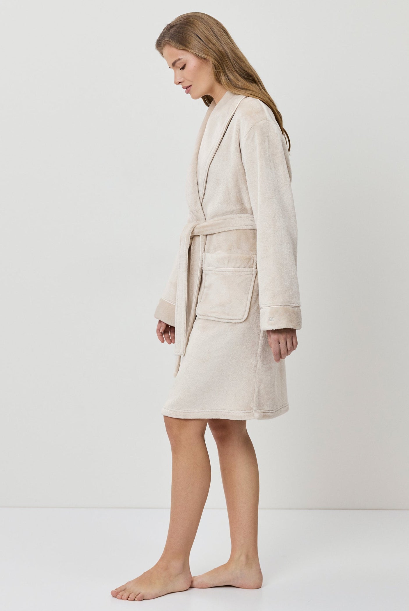 Woman wearing a beige bathrobe on a white background