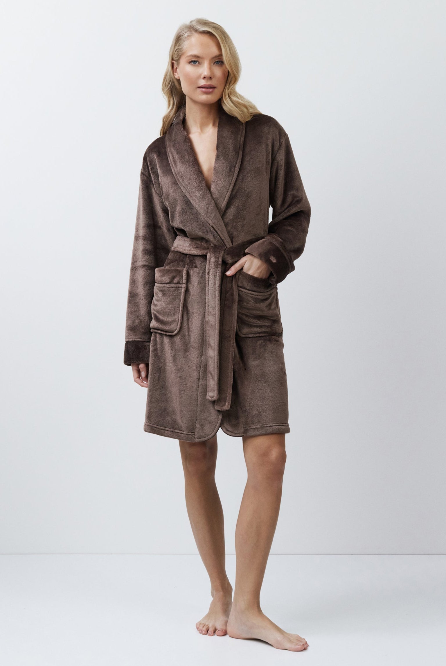 Woman wearing a brown bathrobe against a white background