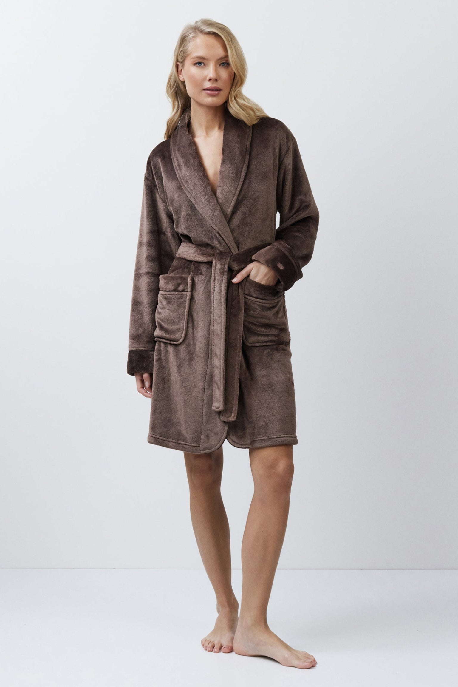 Woman wearing a brown bathrobe against a white background