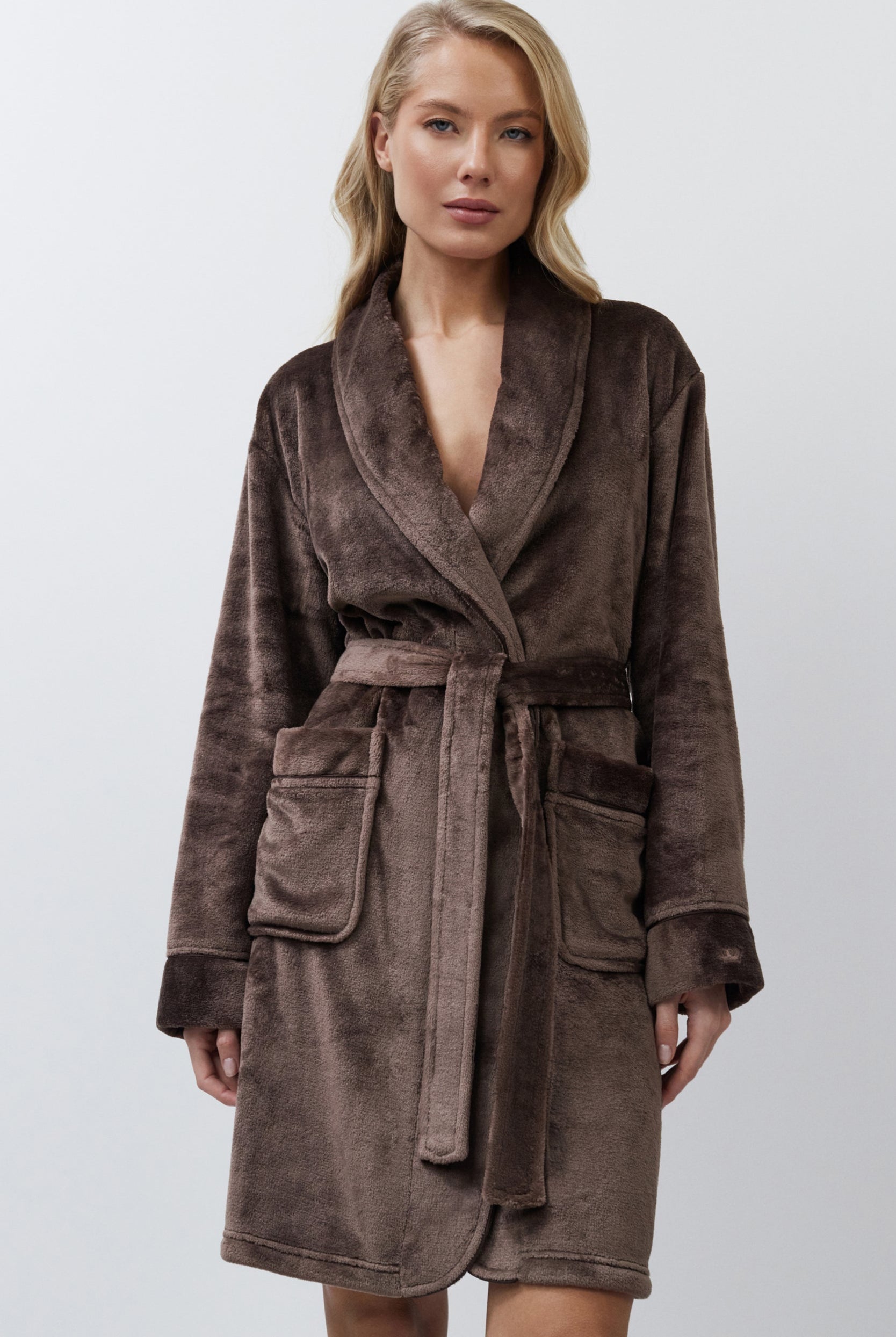 Woman wearing a brown bathrobe against a white background