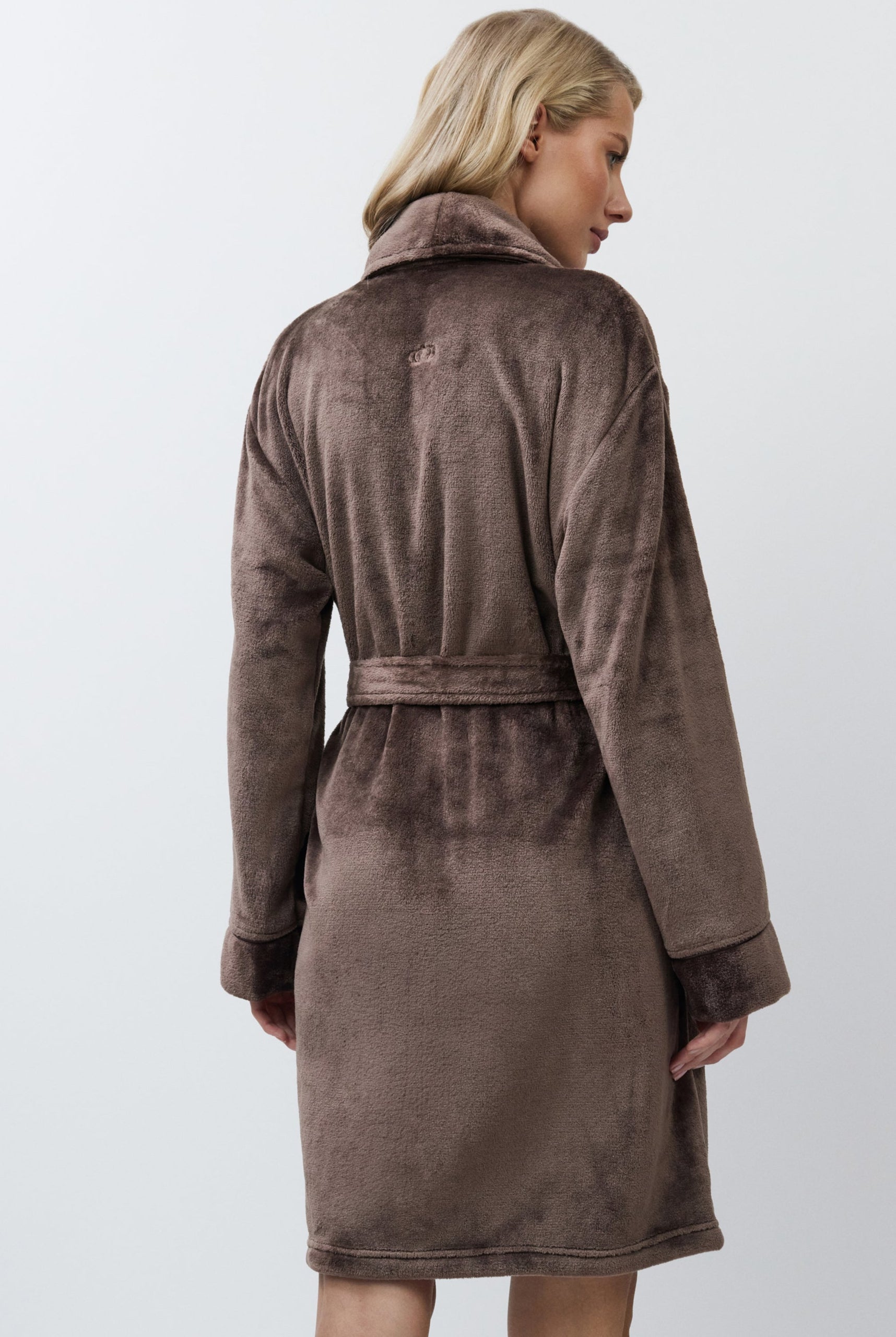 Woman wearing a brown bathrobe against a white background