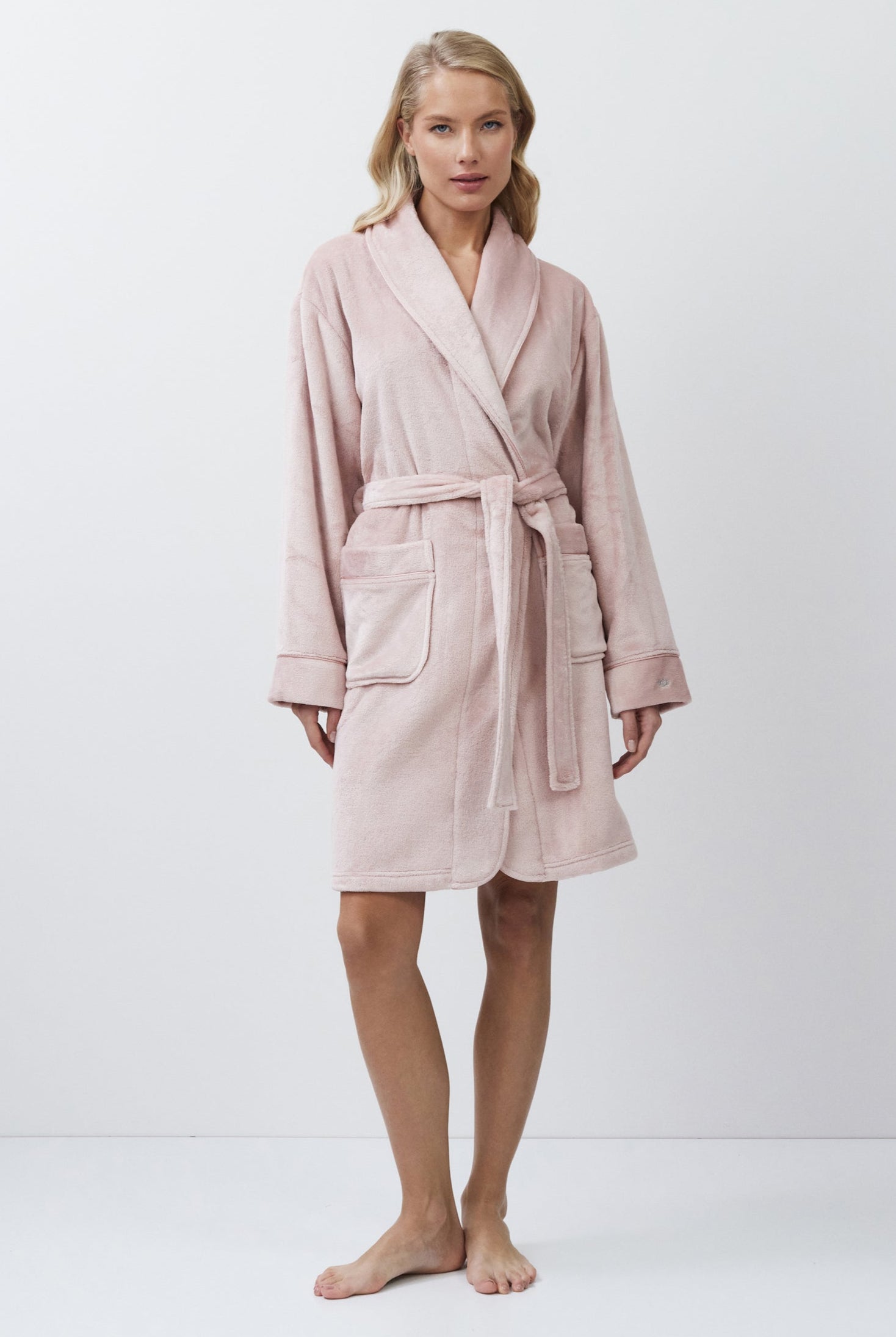 Woman wearing a pink bathrobe against a white background