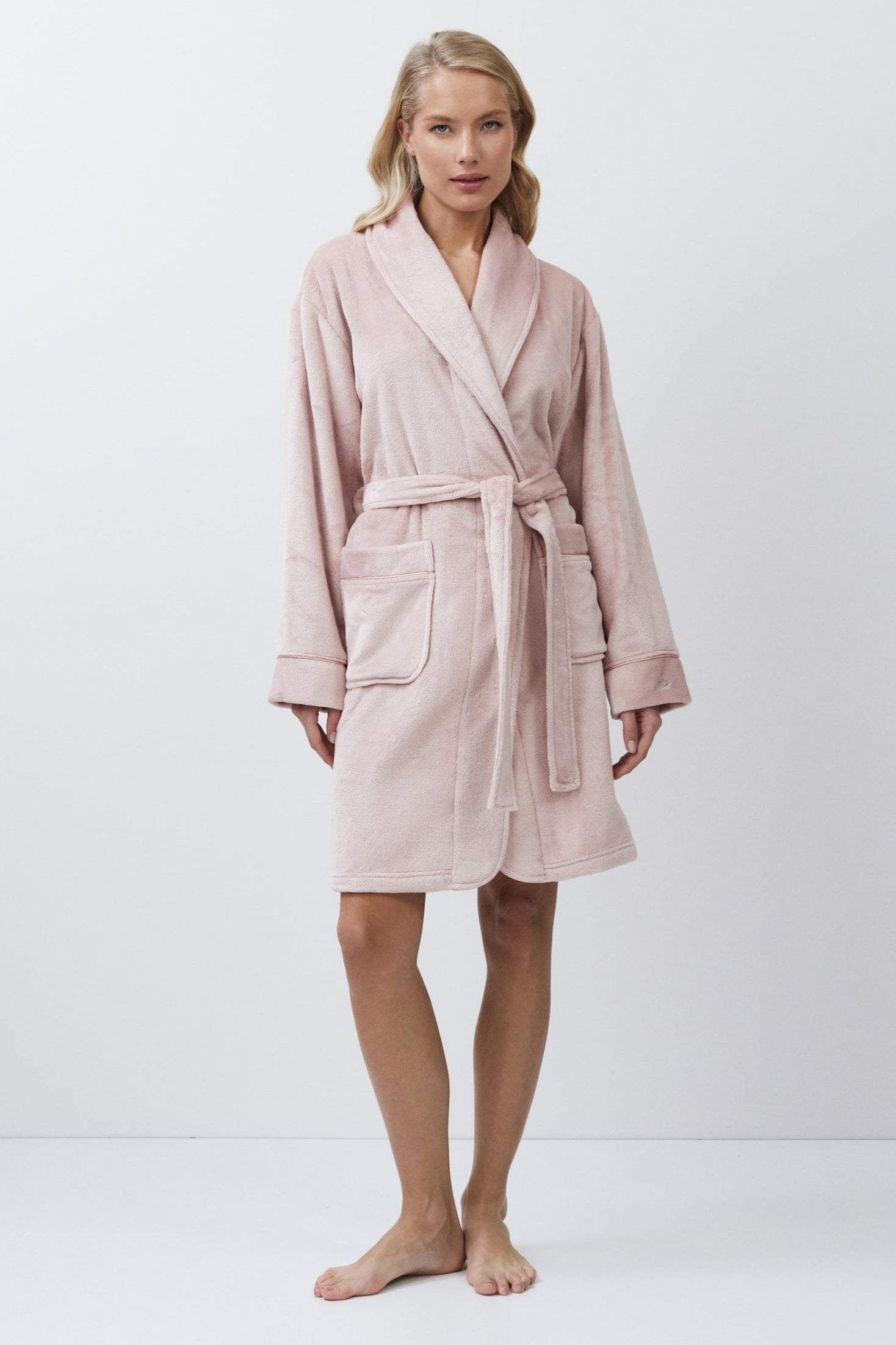 Woman wearing a pink bathrobe against a white background