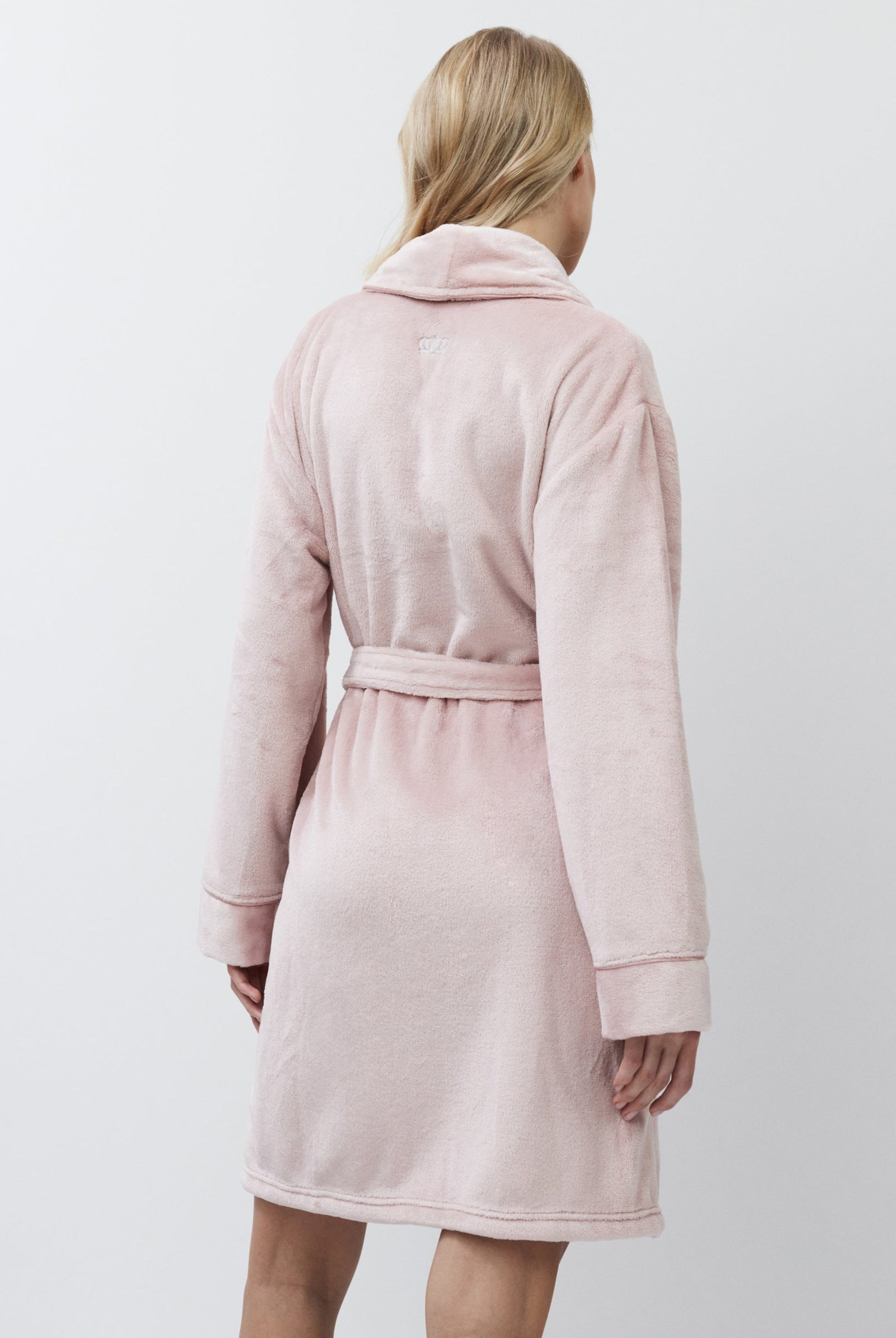 Woman wearing a pink bathrobe against a white background