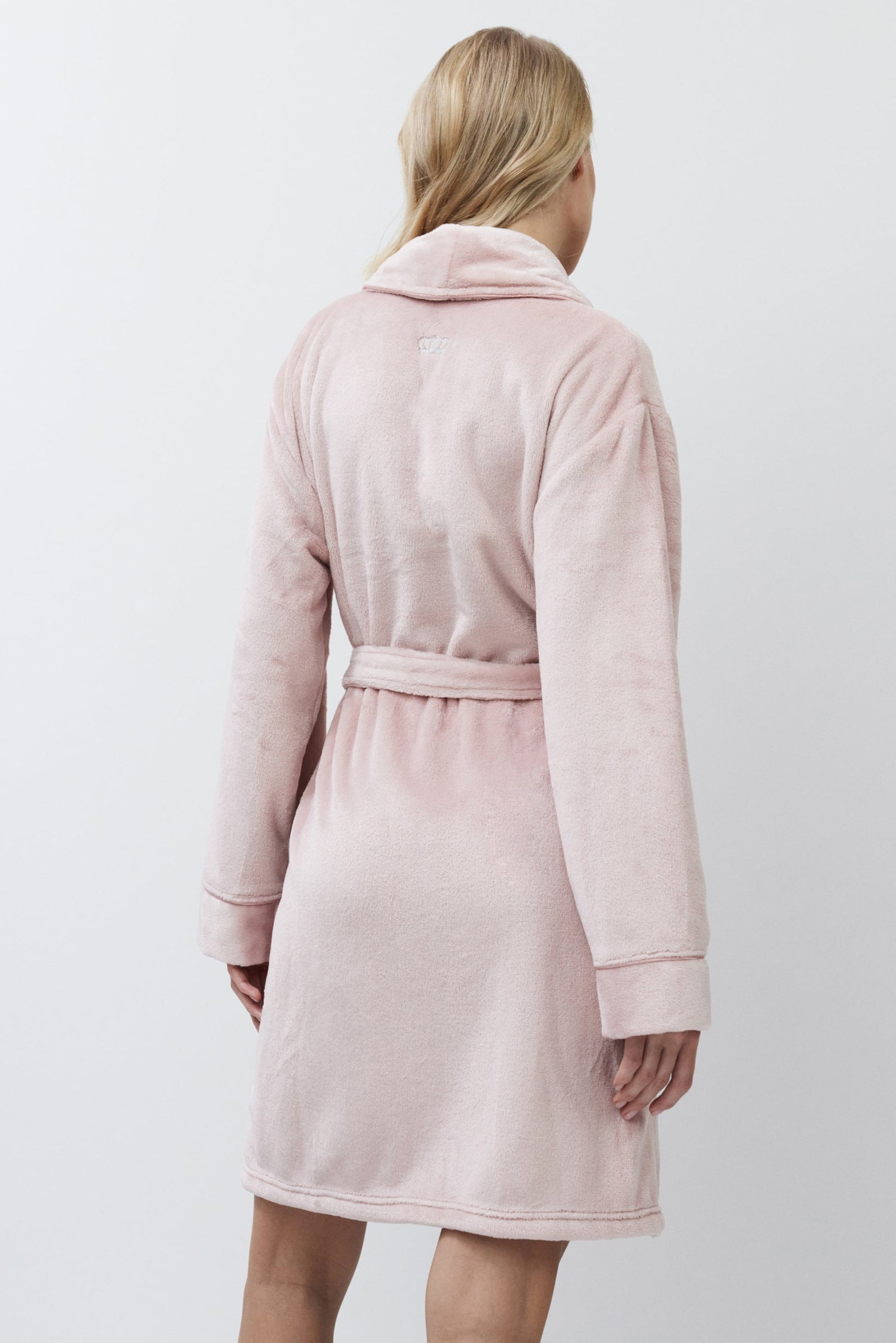 Woman wearing a pink bathrobe against a white background