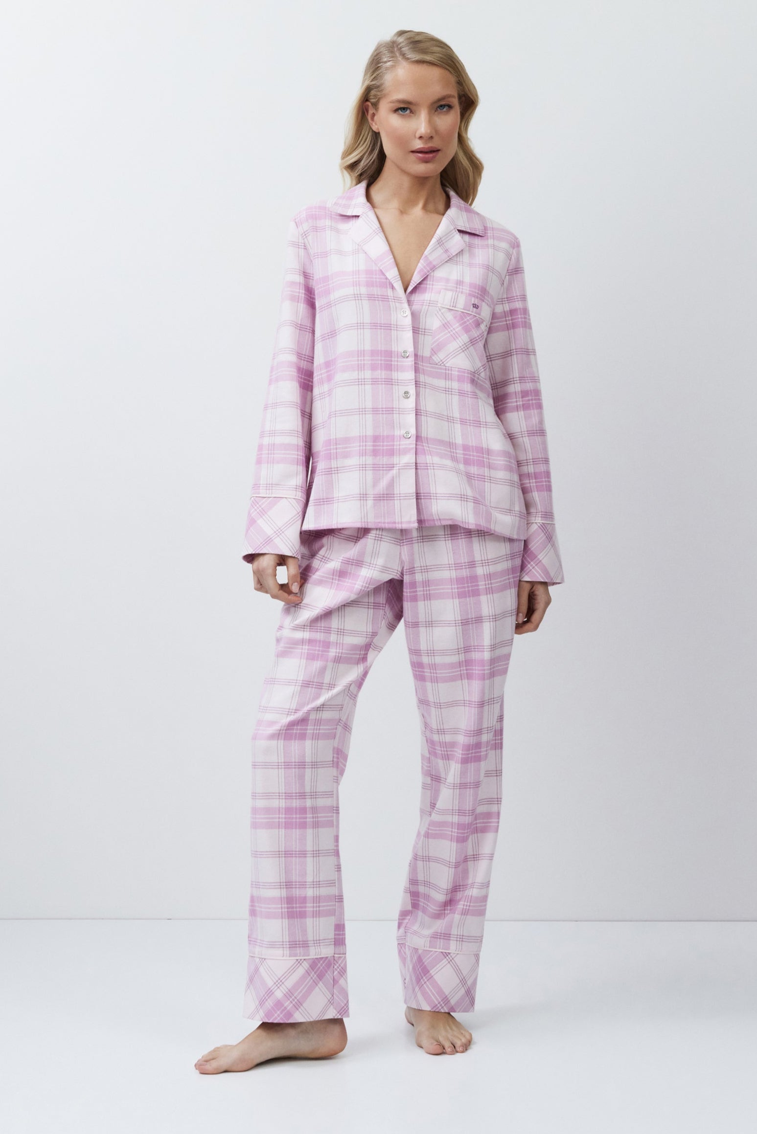 Woman wearing pink plaid pajamas on a white background