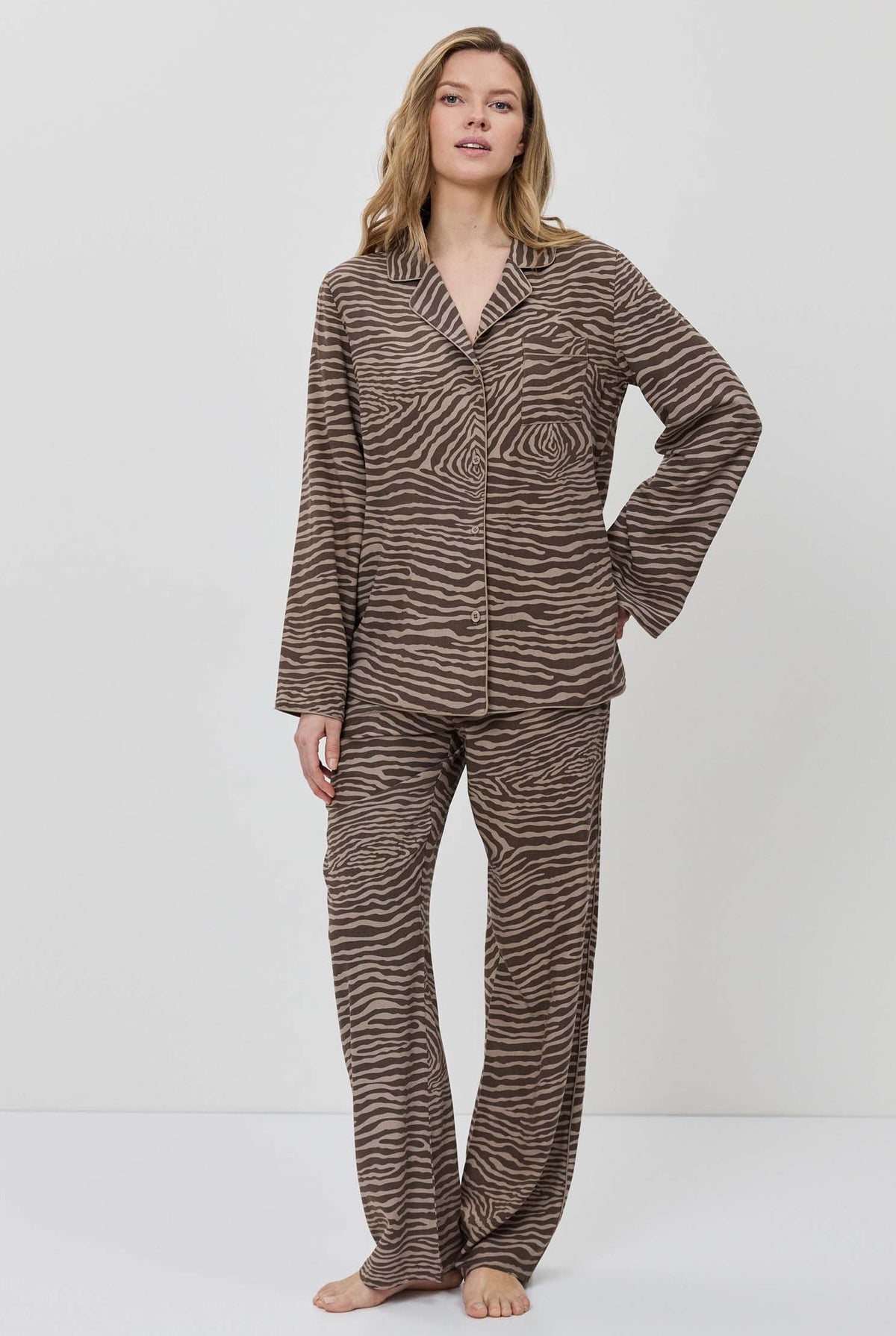 Woman wearing a brown and beige patterned pajama set on a white background.