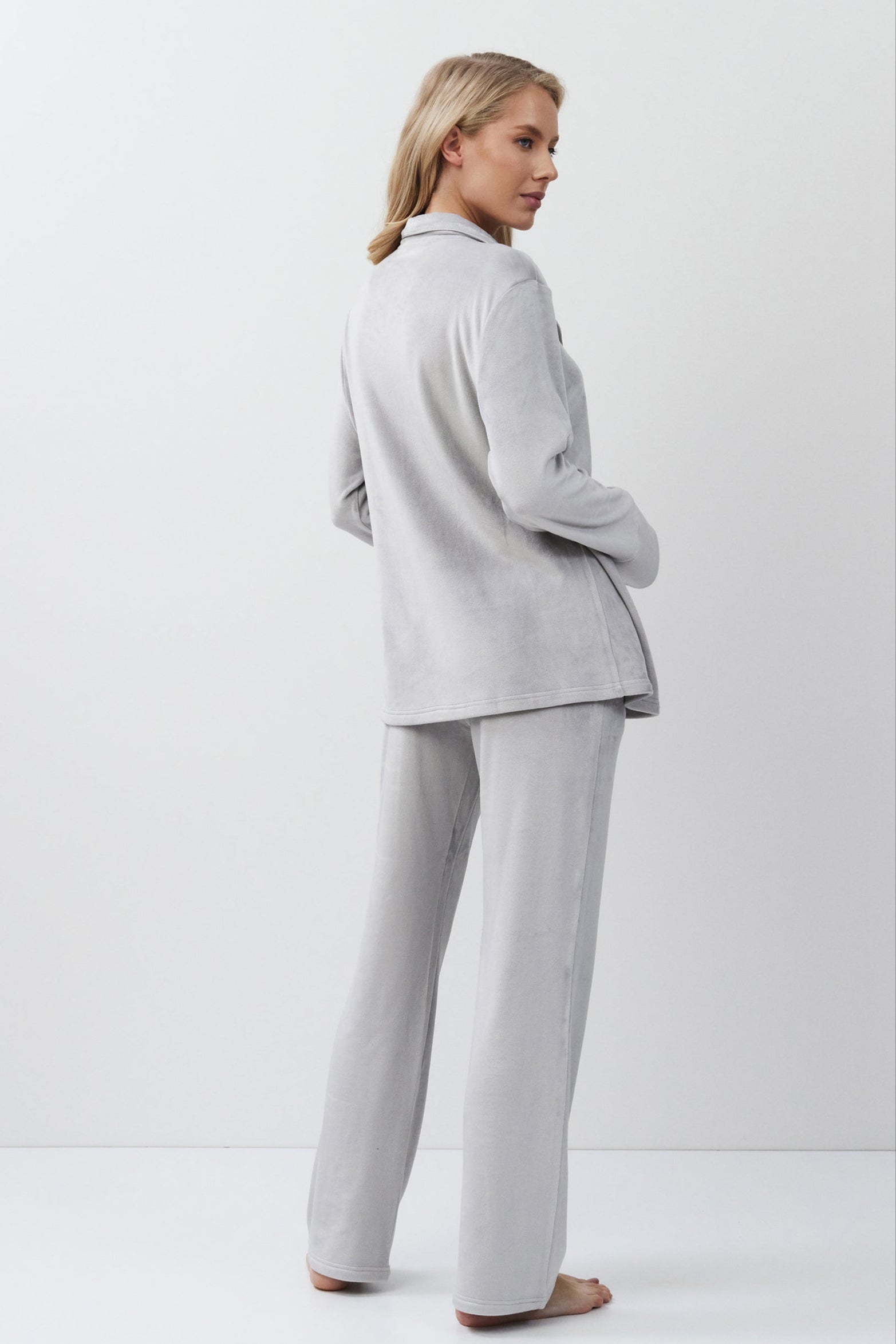 Woman wearing a light gray set standing against a white background