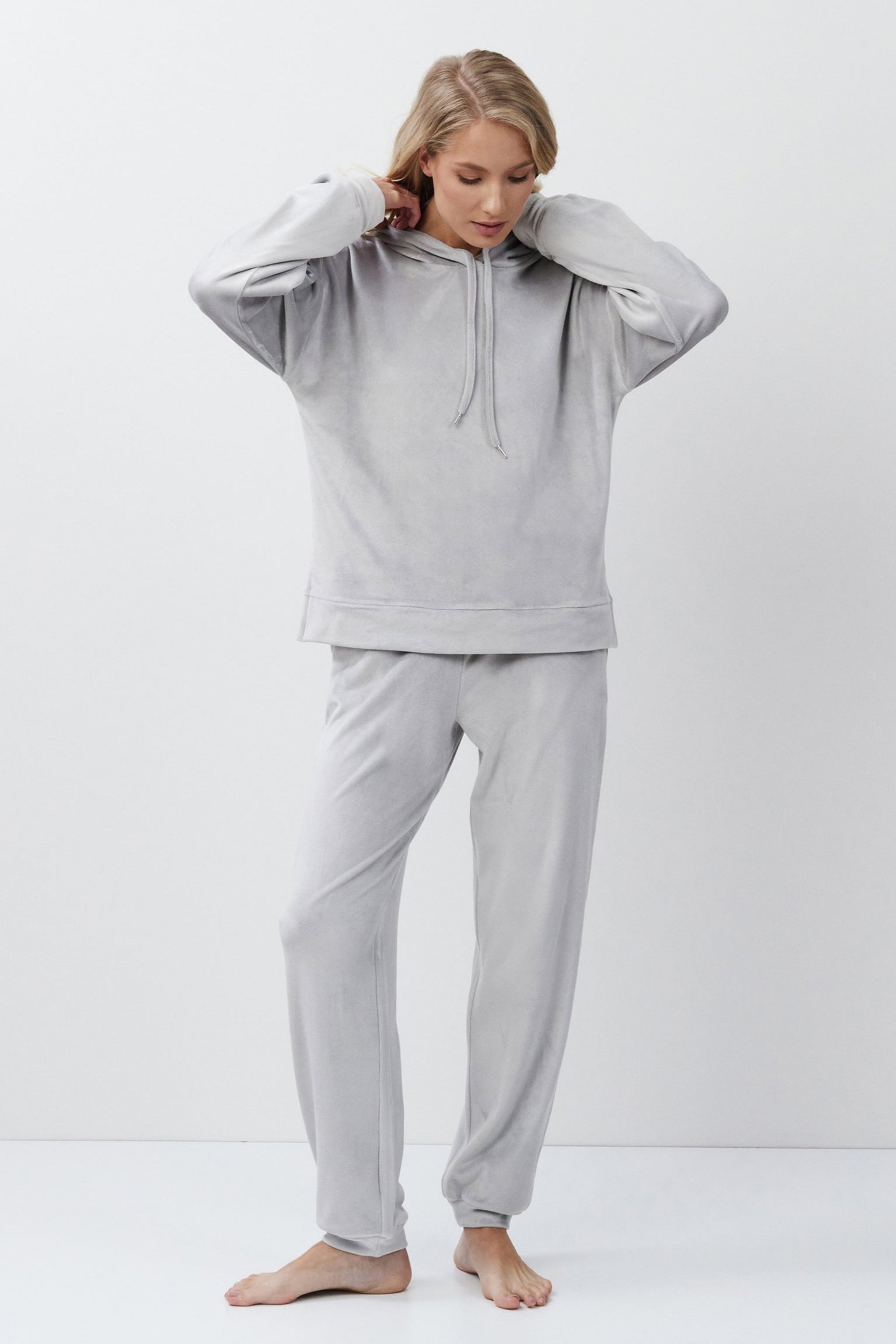 Person wearing a light gray hoodie and pants on a white background