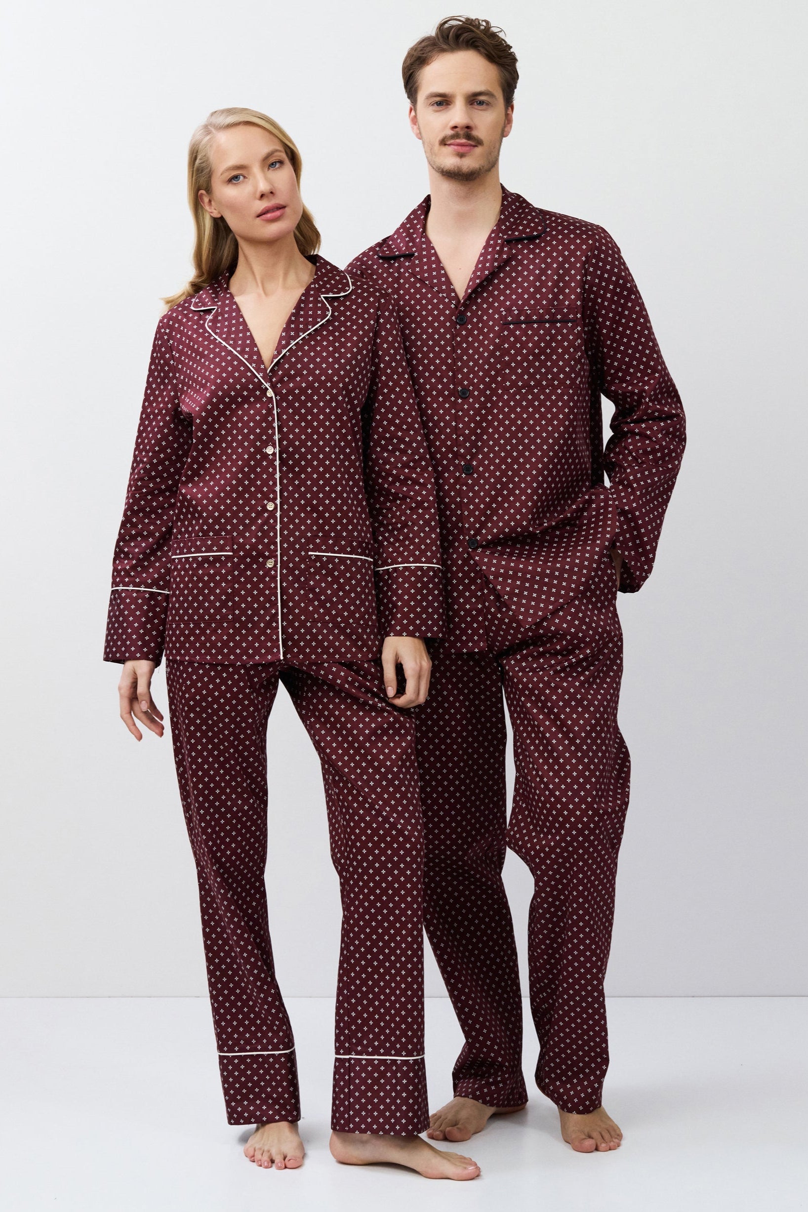 Two people wearing matching burgundy pajamas on a white background