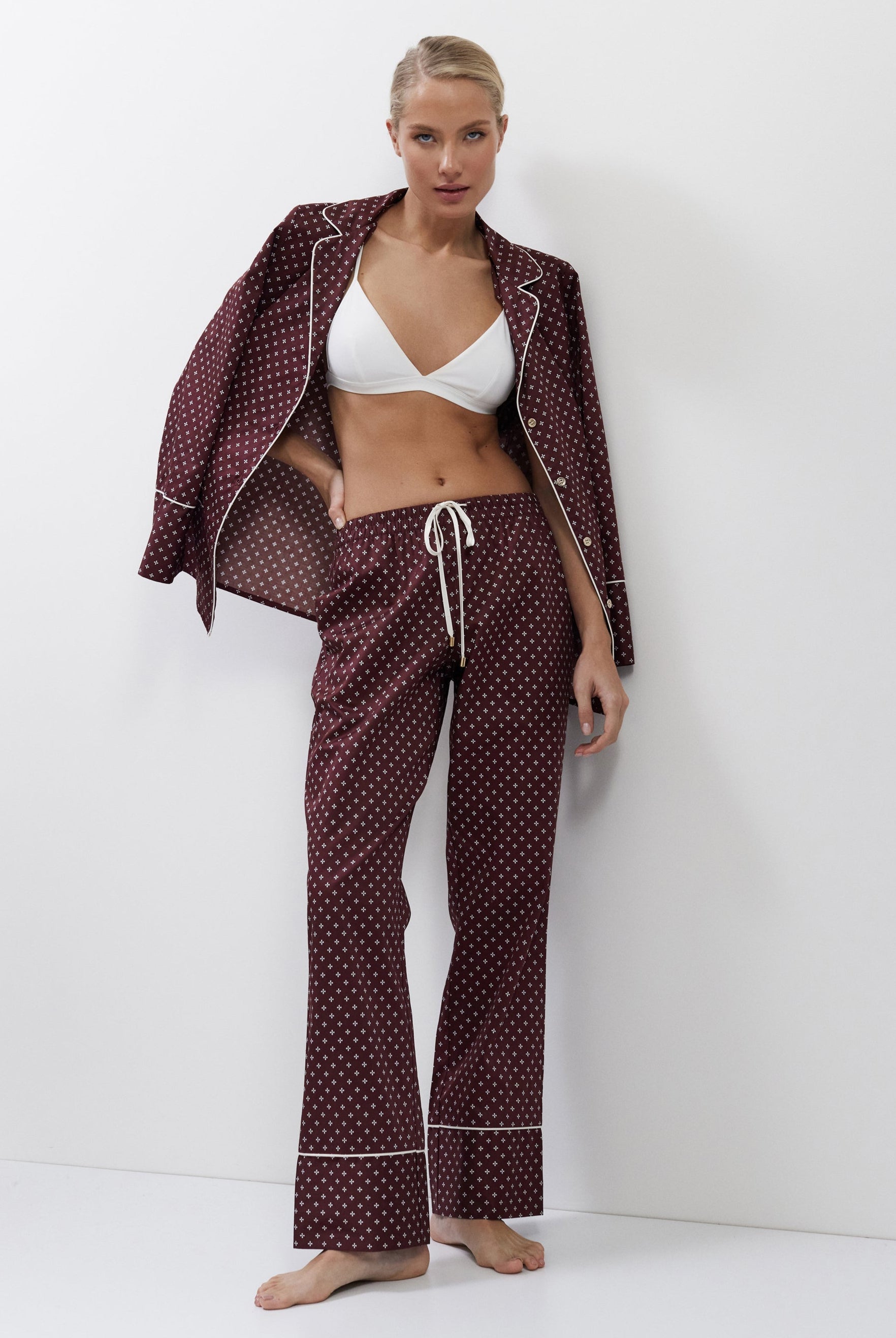 Woman wearing a burgundy pajama set with a white top against a white background