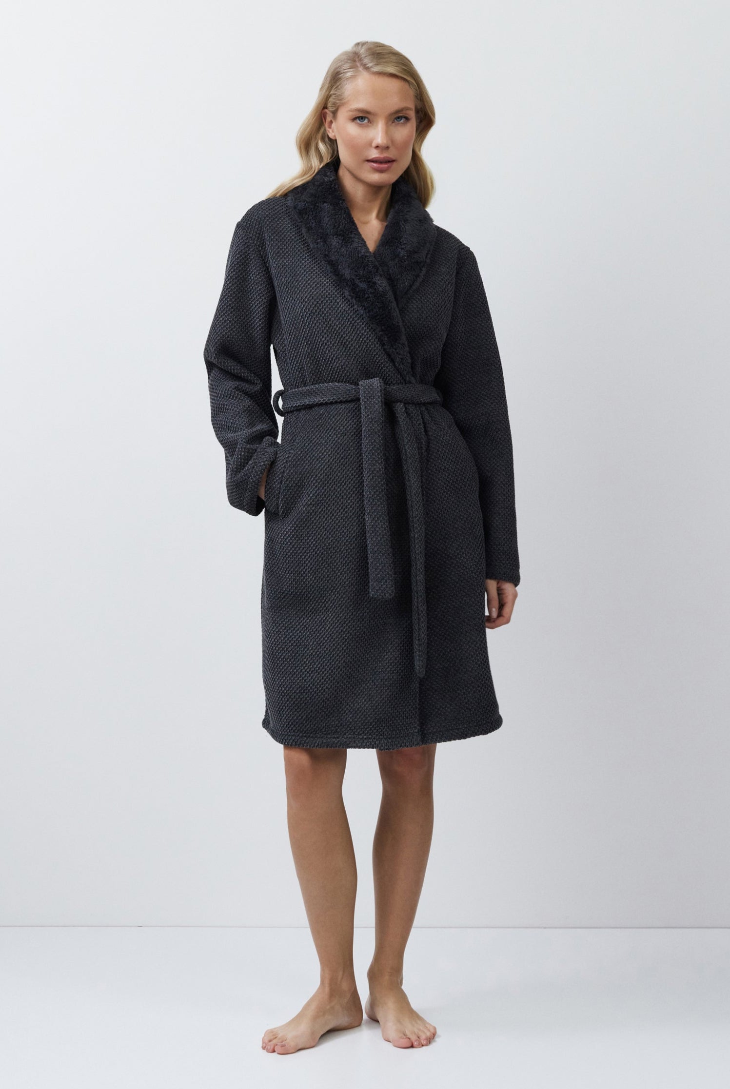 Woman wearing a dark gray bathrobe against a white background