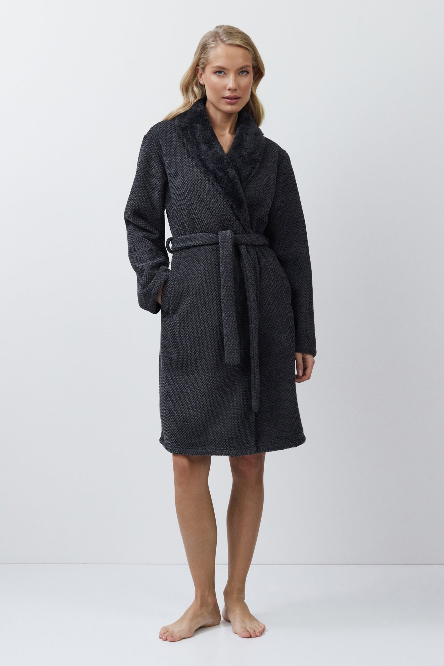 Woman wearing a dark gray bathrobe against a white background