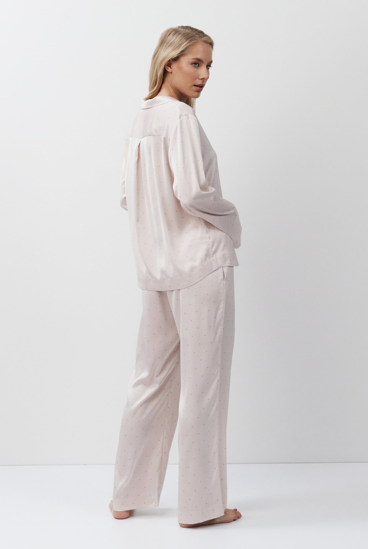 Woman wearing a light pink pajama set against a white background