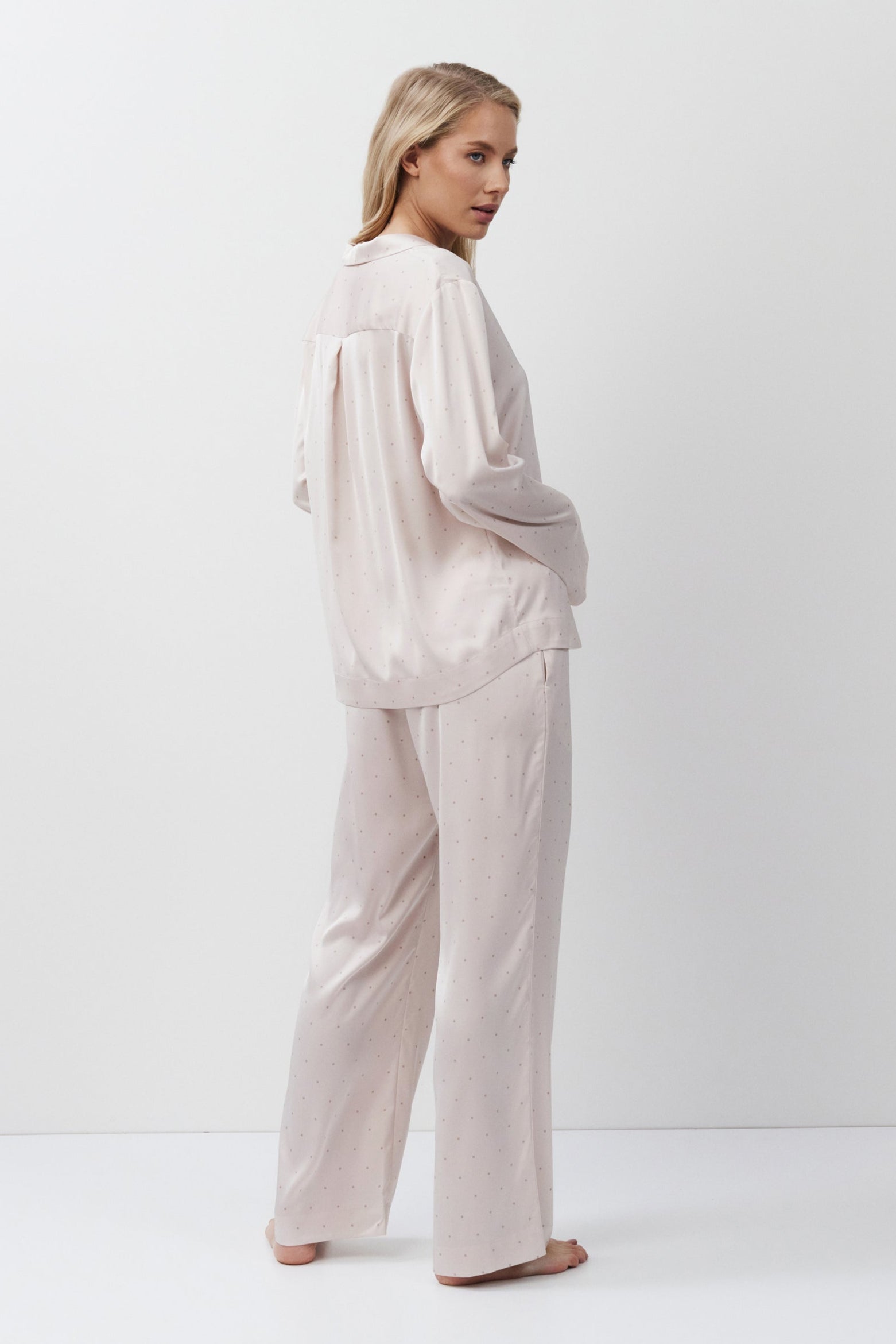 Woman wearing a light pink pajama set against a white background