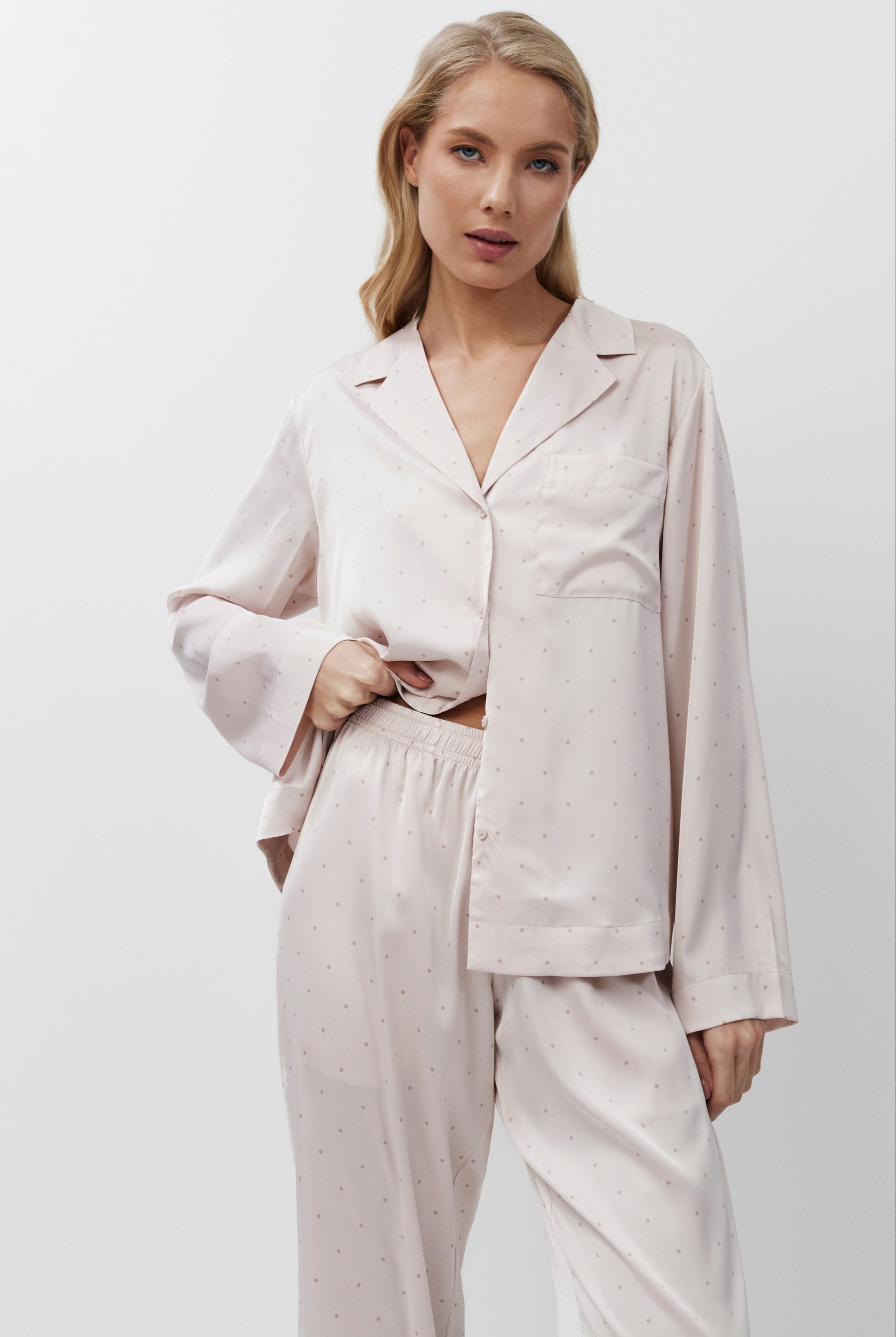 Woman wearing a light pink pajama set against a white background