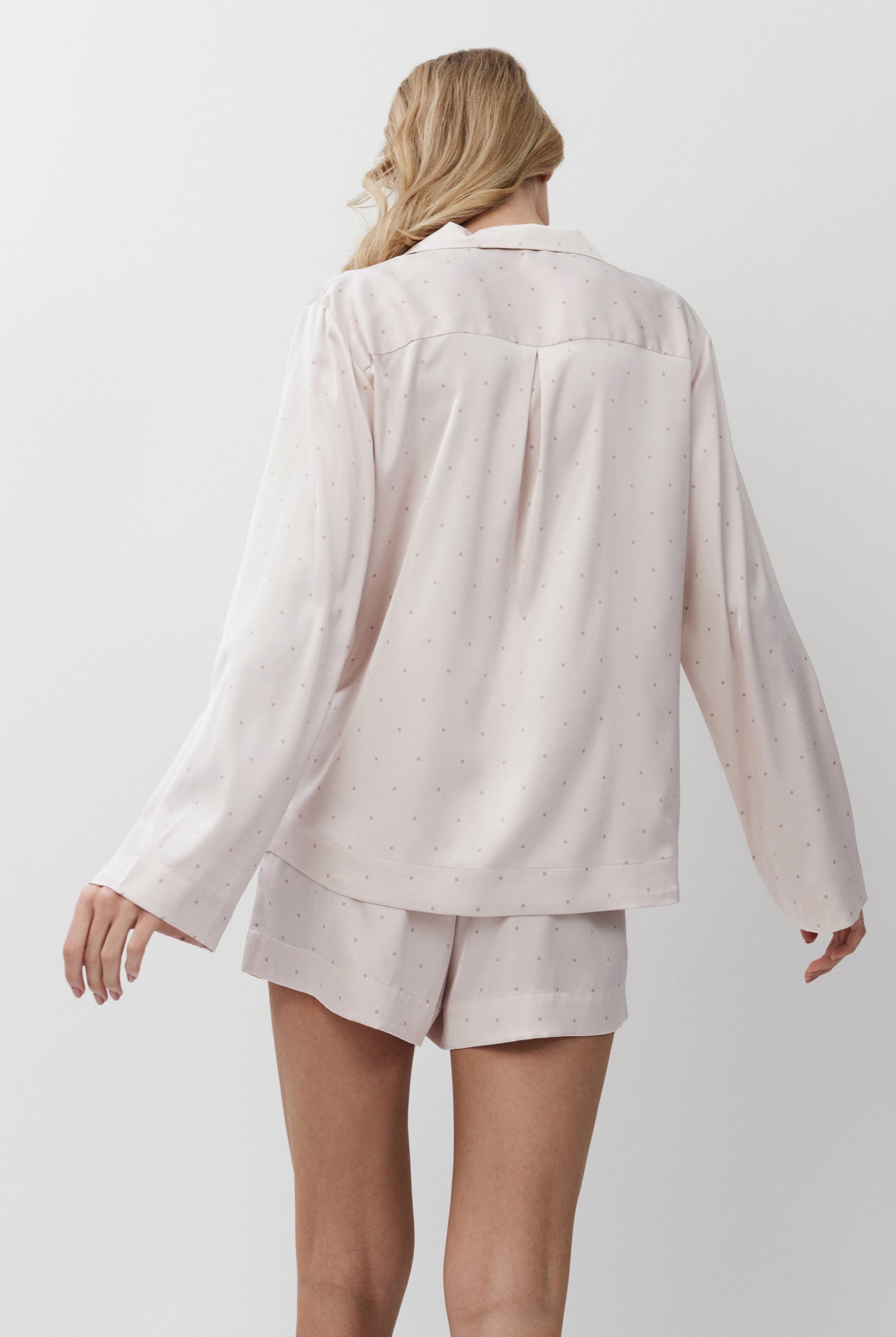 Person wearing a light pink pajama set on a white background