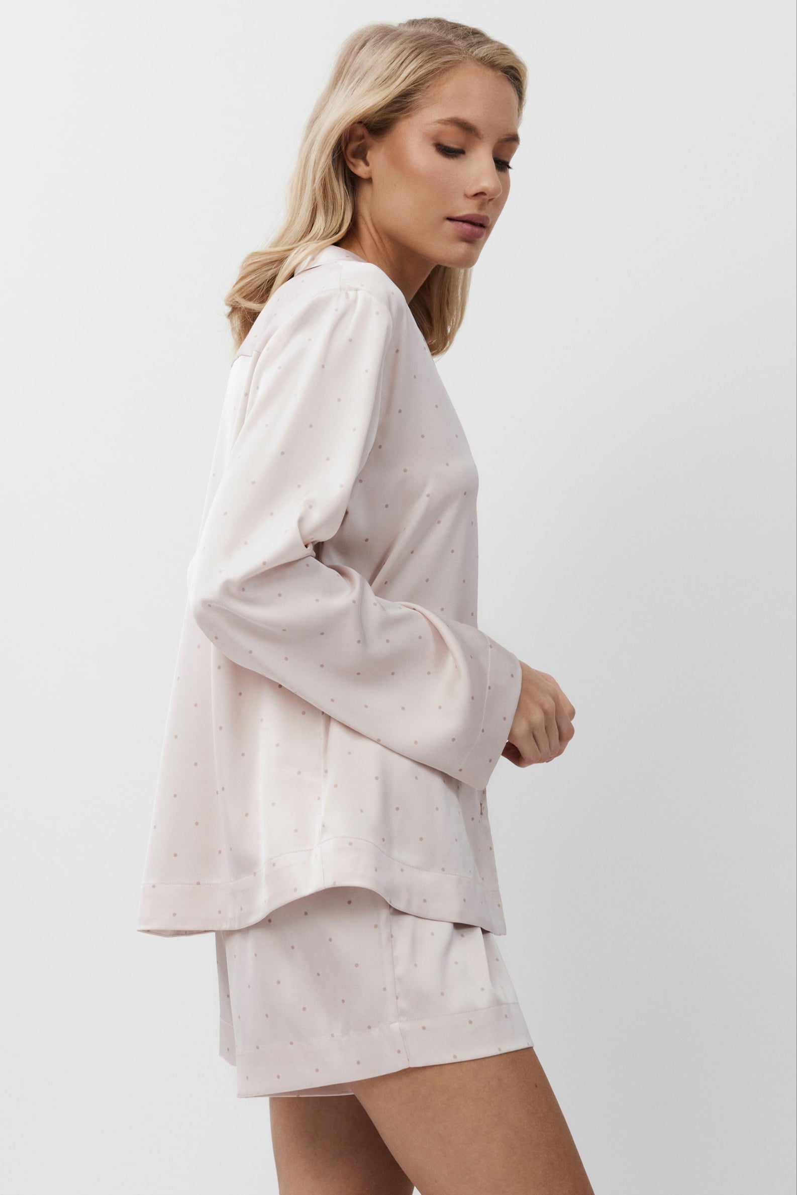 Woman wearing a light pink pajama set on a white background