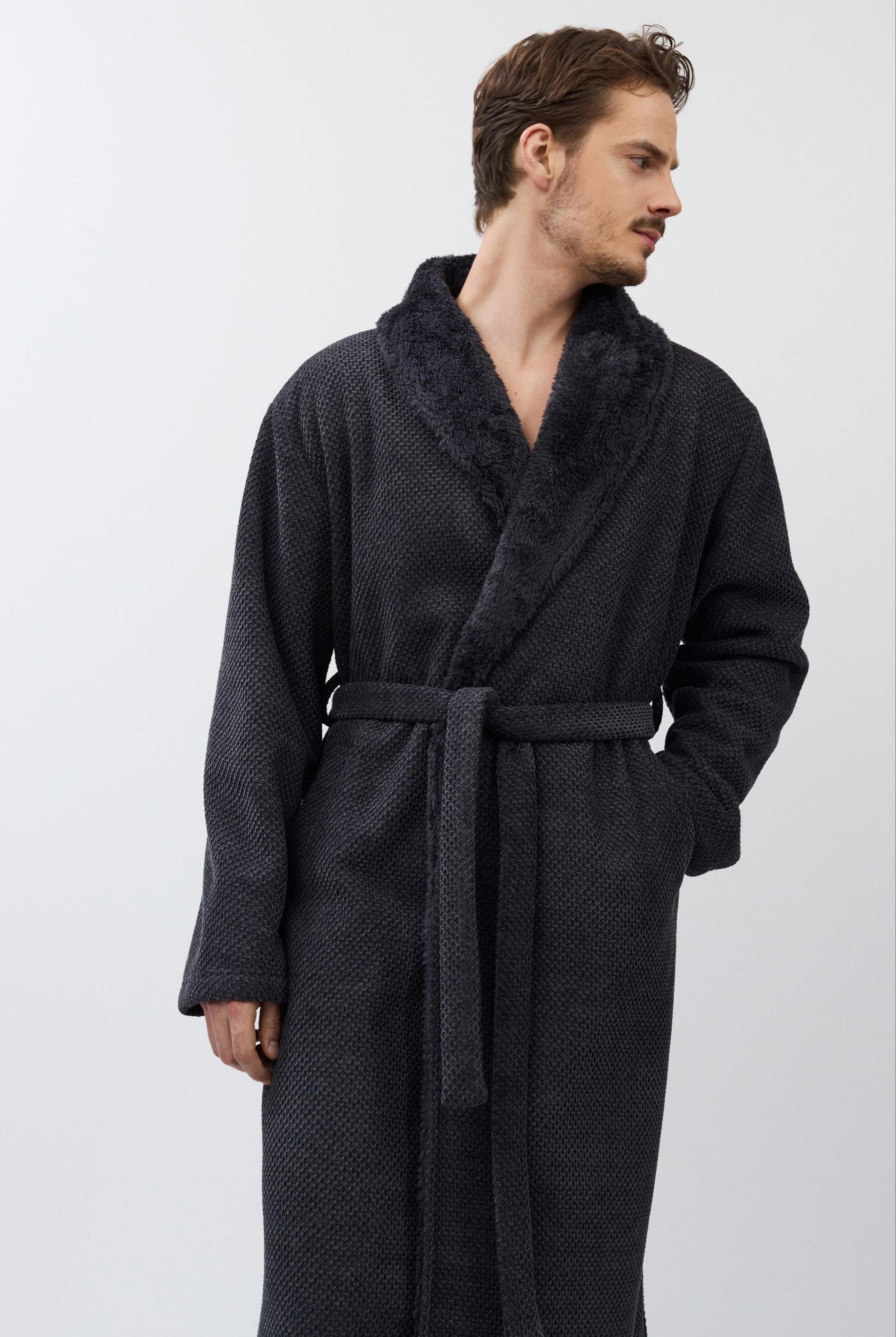 Man wearing a dark gray bathrobe with textured fabric on a white background